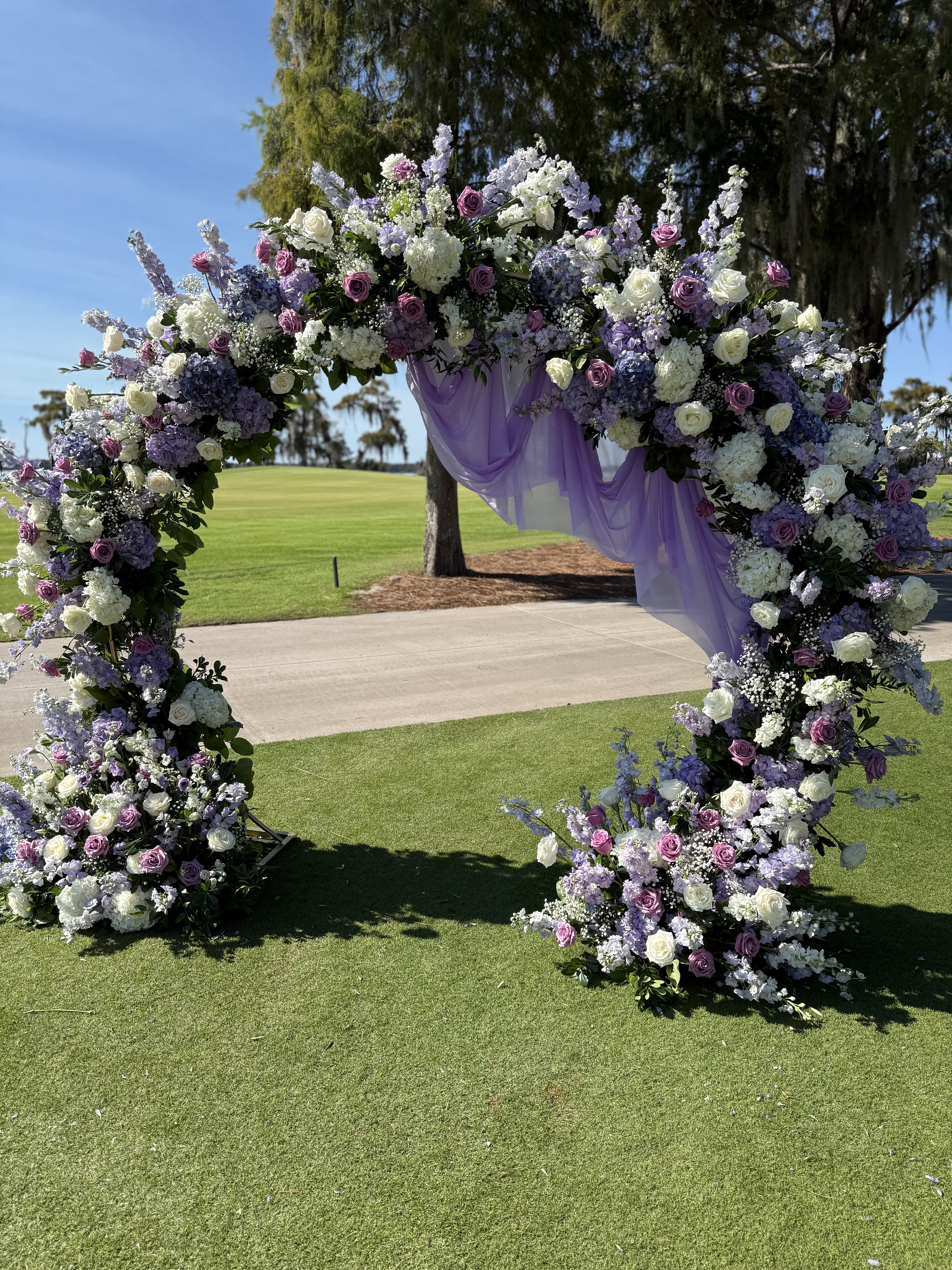 Enchanted Garden Arch - A dreamy floral arch designed to transform your ceremony into a fairytale moment. Featuring lush roses, hydrangeas, stock, lisianthus, and delicate baby’s breath in soft lavender and ivory tones.