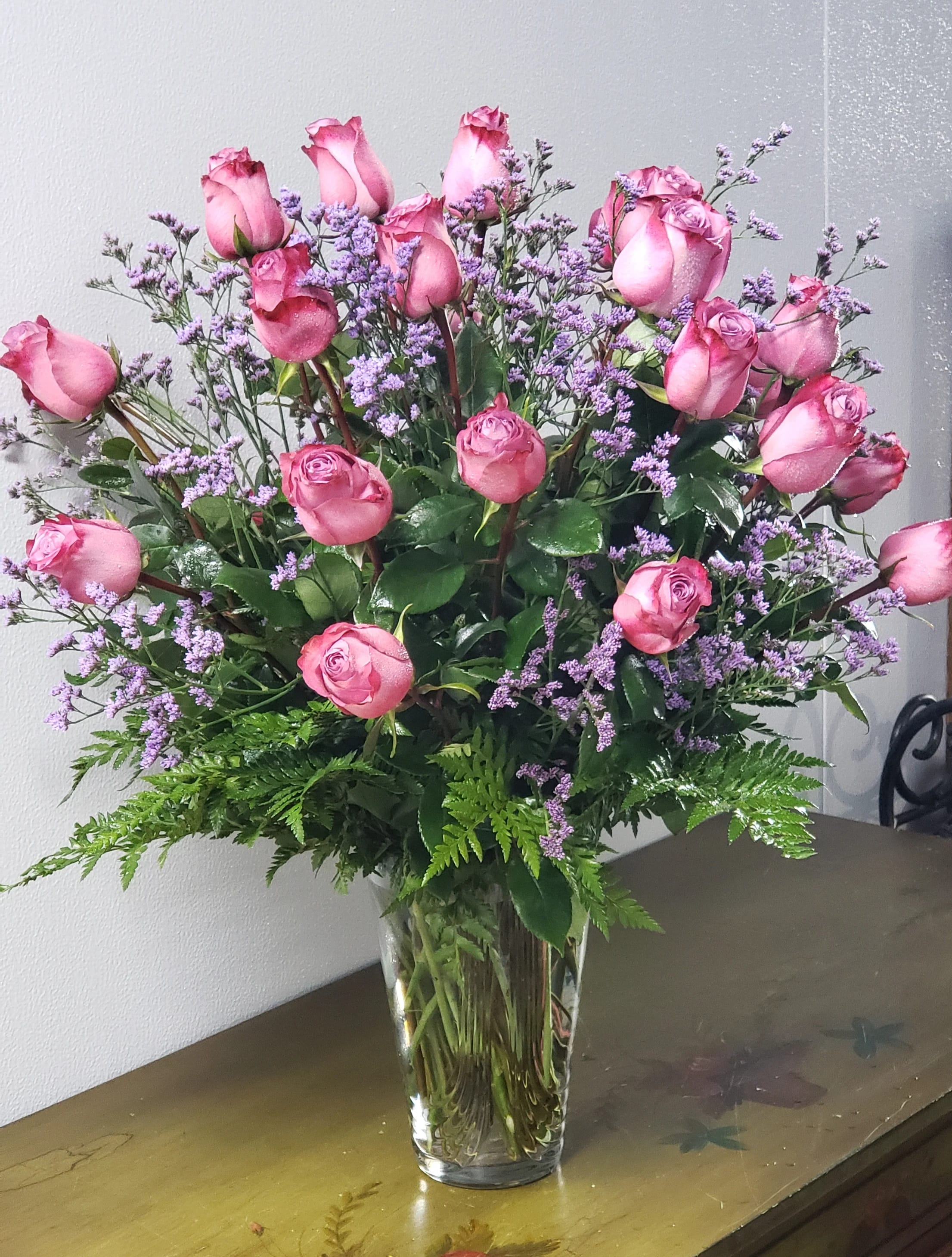 Pink roses and purple filler flowers in a clear glass vase