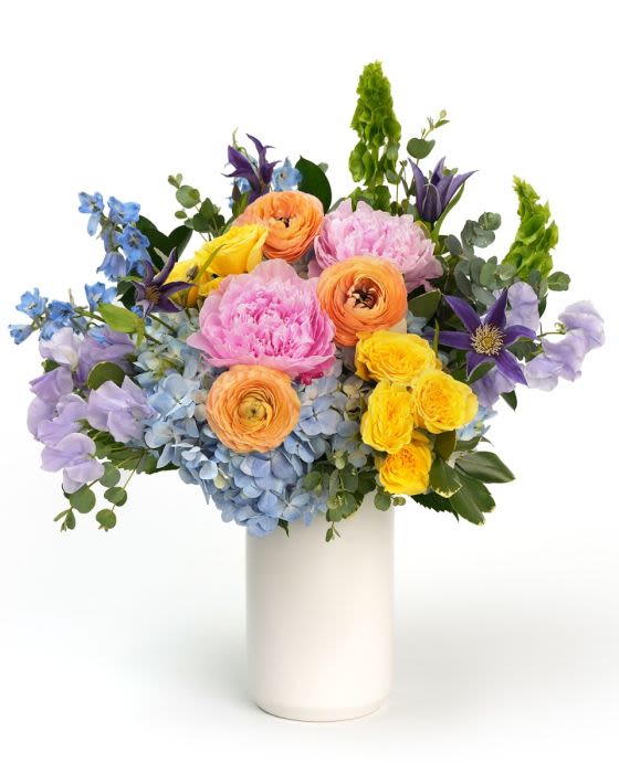 Spring Serenity - A soft mix of pastel blooms in pink lavender yellow, and blue, designed with fresh greenery in a serene garden style.