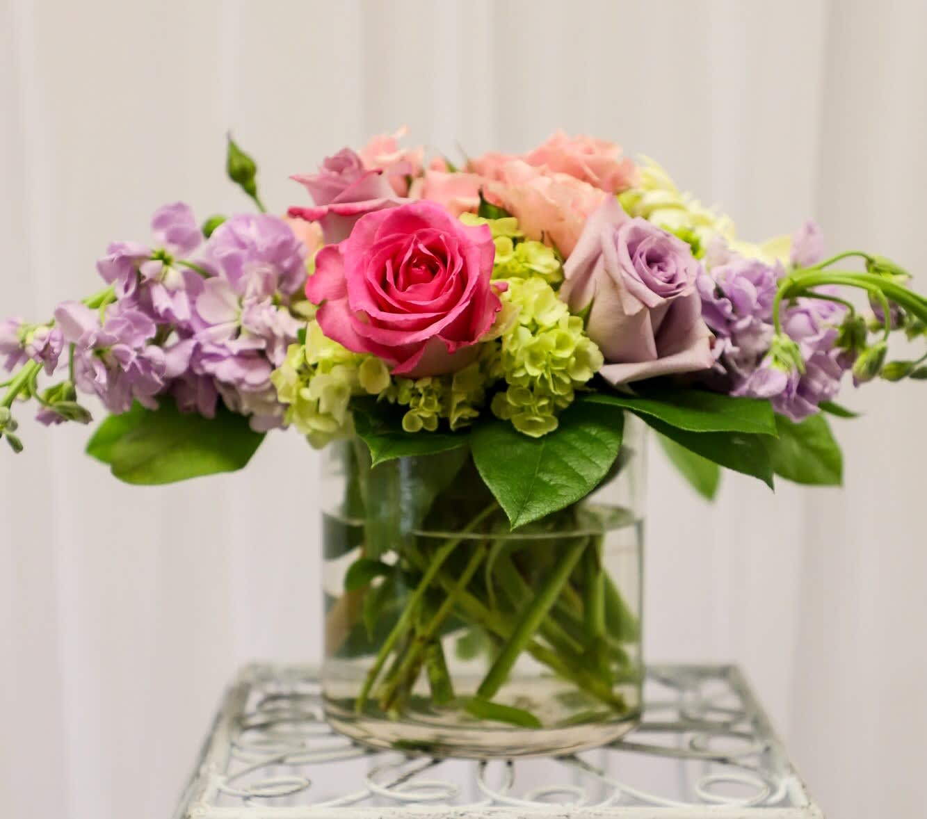 Pink and lavender roses with purple flowers in a glass vase