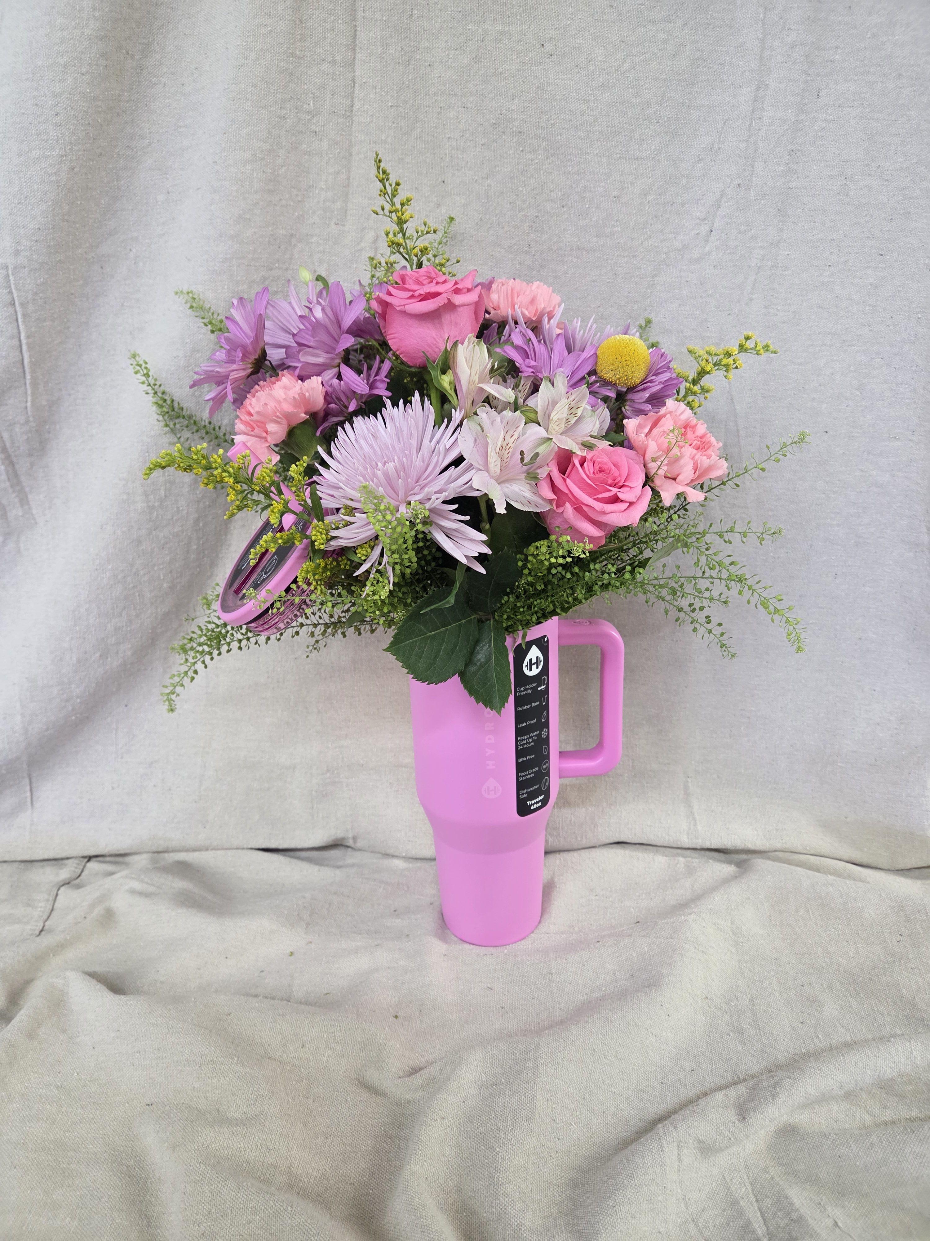 Pink and purple mixed bouquet arranged in a bright pink handled travel tumbler