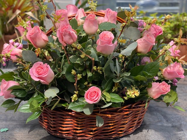 Pink roses arranged in a wicker basket.