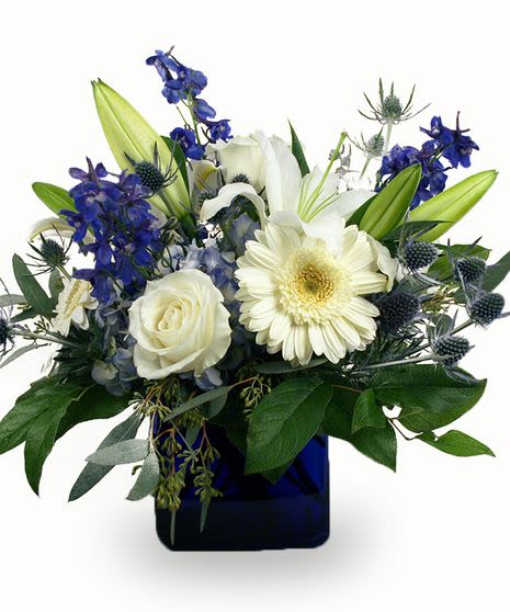 Blue &amp; White Serenity Cube Arrangement  - Bring peaceful elegance to any space with our Blue &amp; White Serenity cube arrangement , a timeless blend of creamy white roses, lilies, gerbera daisies, and soft blue delphinium, accented with striking blue thistle and lush greenery. Designed in a rich midnight-blue cube vase, this arrangement radiates calm, grace, and refined beauty. It’s an ideal choice for sympathy tributes, get-well wishes, corporate gifting, or simply adding a touch of classic style to the home. Handcrafted by local Omaha floral designers using the freshest seasonal blooms, this arrangement offers a soothing palette that conveys comfort and heartfelt sentiment. *** All cube arrangements are short and compact. **** Features White roses, lilies, gerbera daisies, and premium delphinium Accented with blue thistle and fresh greenery Arranged in a deep-blue glass cube vase Same-day delivery available if ordered by 12 noon central time 