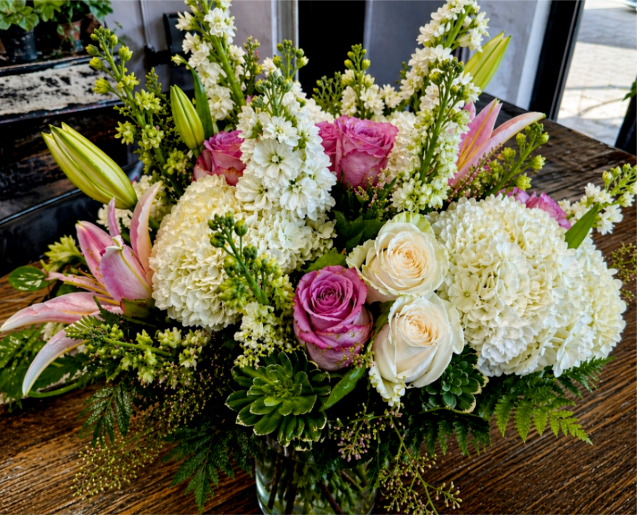 Pink and white mixed bouquet in a glass vase with lilies and roses