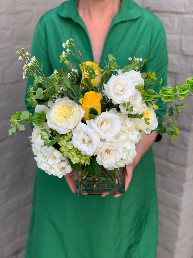 White and yellow flower arrangement in a square glass vase