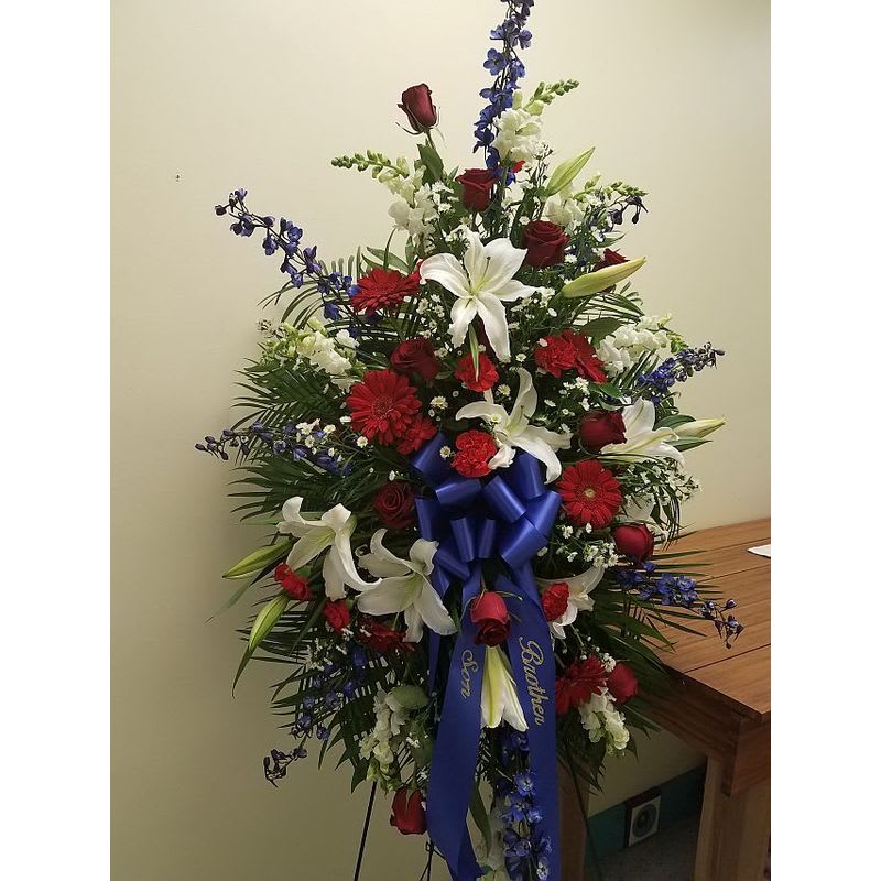 Patriotic Tribute - Fitting tribute for the person who served their country. A standing spray of Red white and blue flowers. Ribbon can be customized