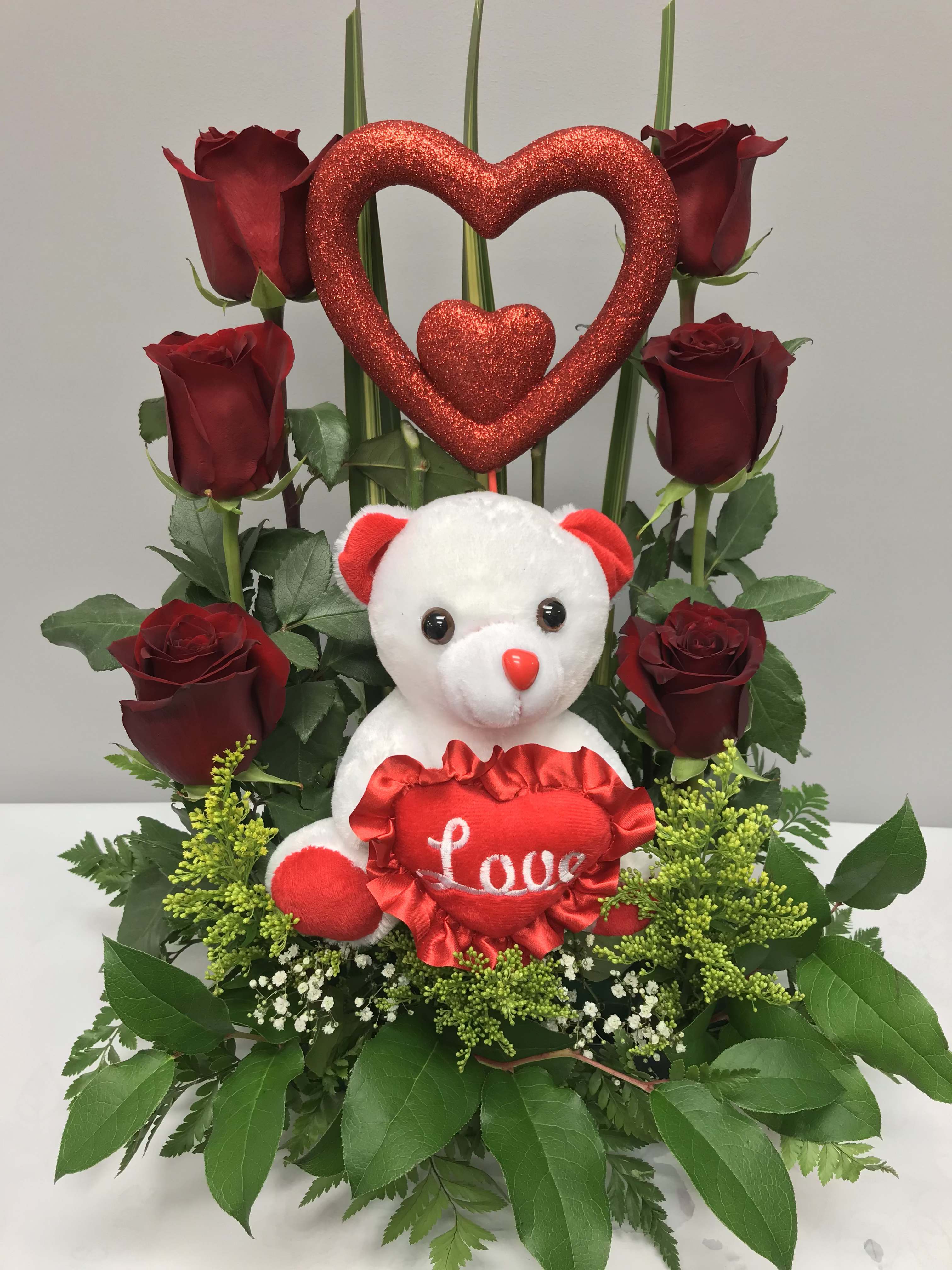 Red roses arranged with a teddy bear and glittery heart decoration