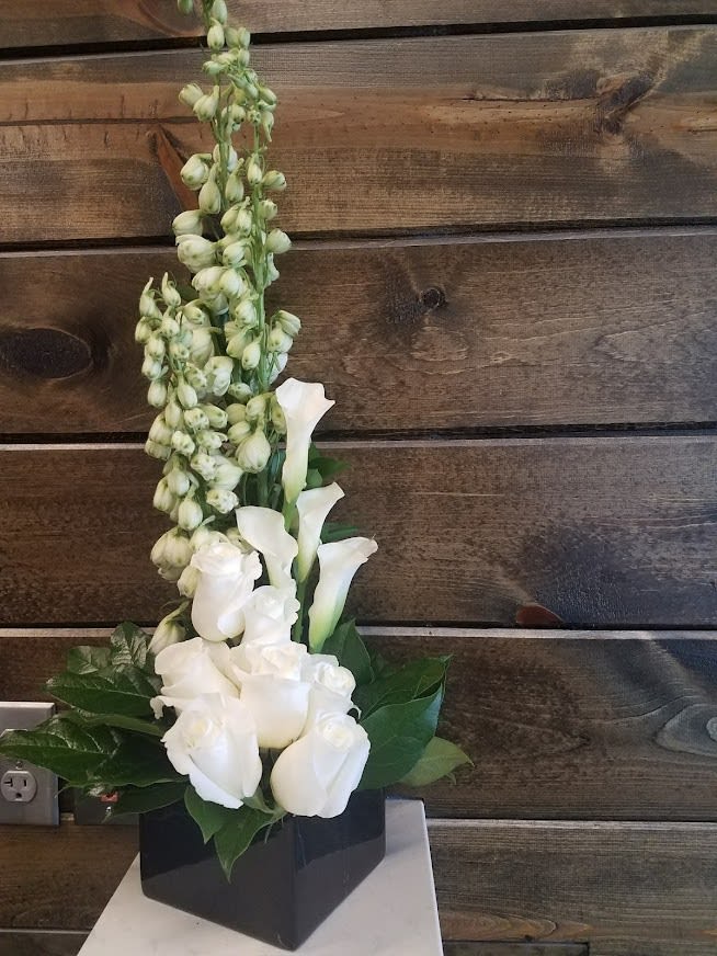 Simply White  - Liner Design of White Delph or snapdragons White mini Callas, white roses and tropical leaves 
