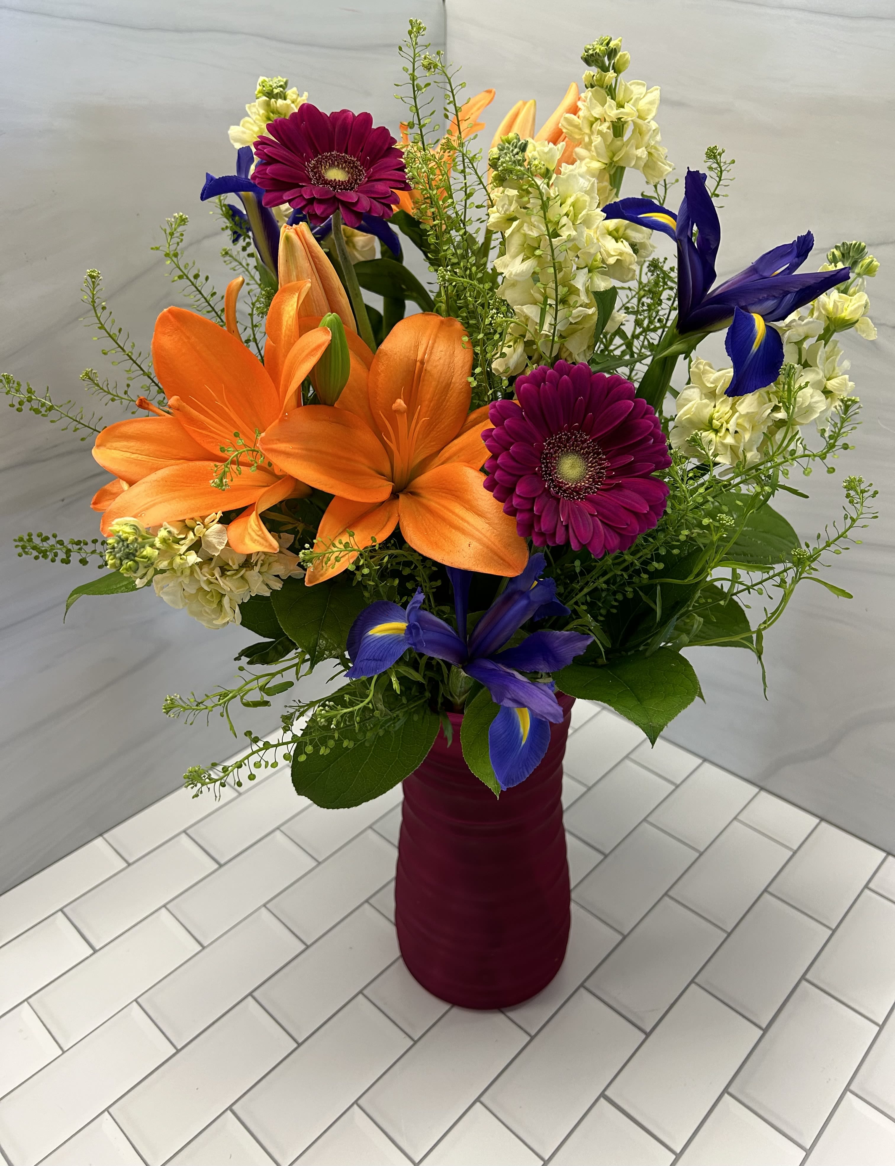 Stellar Mom - Bouquet will be delivered approximately as pictured.   This bold vased arrangement is a show stopper with an array of vibrant hues.  Featuring lilies, stock, hot pink gerbera daisies, iris and fun greens - this is one for a "stellar mom"!