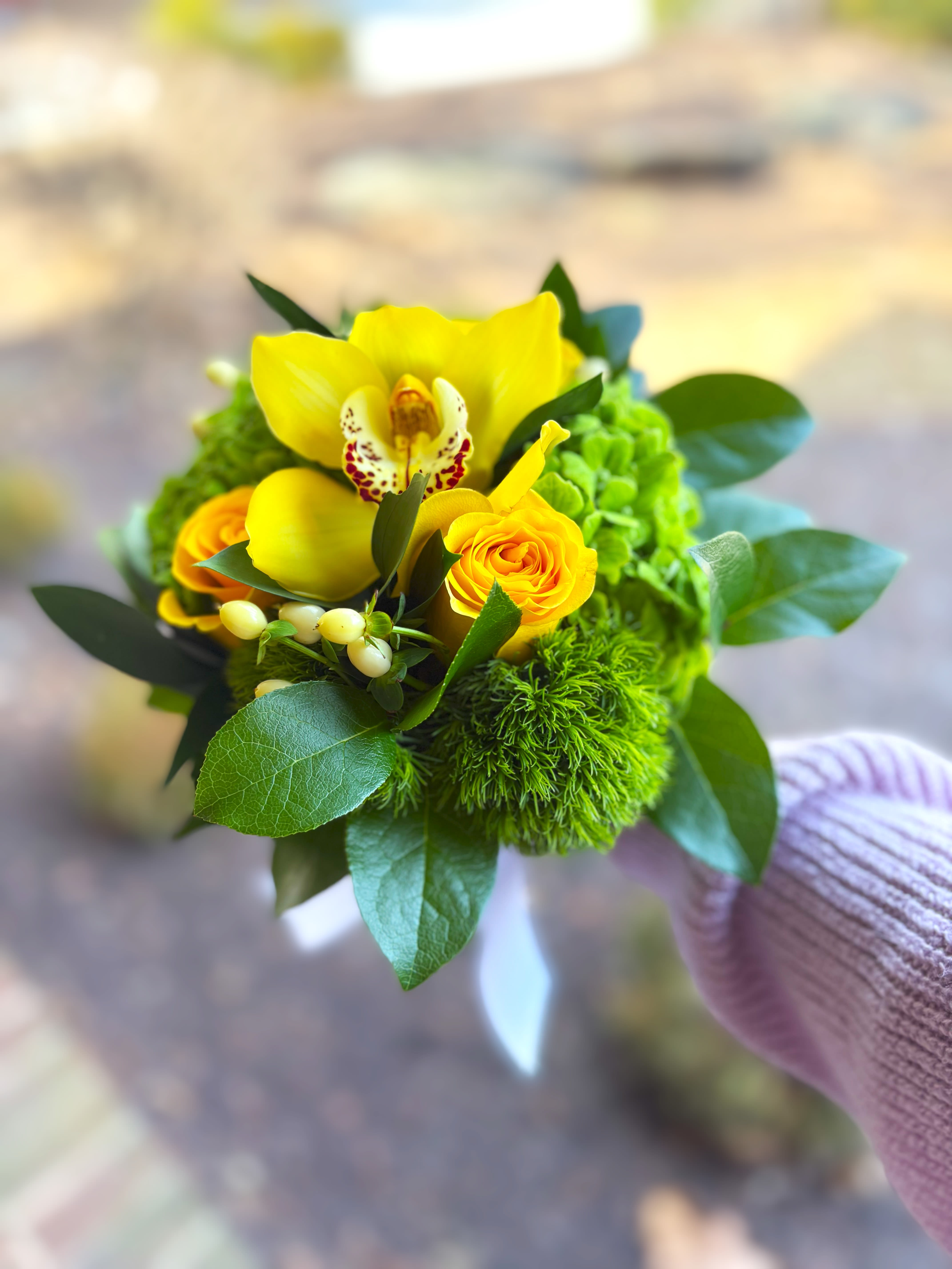 Small bouquet with yellow orchids and roses in a hand