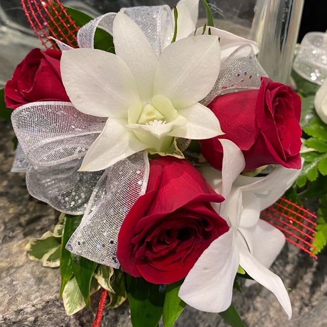 Red and White wristlet corsage - We feature red spray roses and white dendrobium orchids in this lovely wrist corsage. Accent with red glitter ribbon, white sheer ribbon or any color ribbon you choose.   PLEASE CALL THE SHOP AT (617)244-4422 FOR ALL CORSAGE OR BOUTONNIERE ORDERS. THANK YOU.