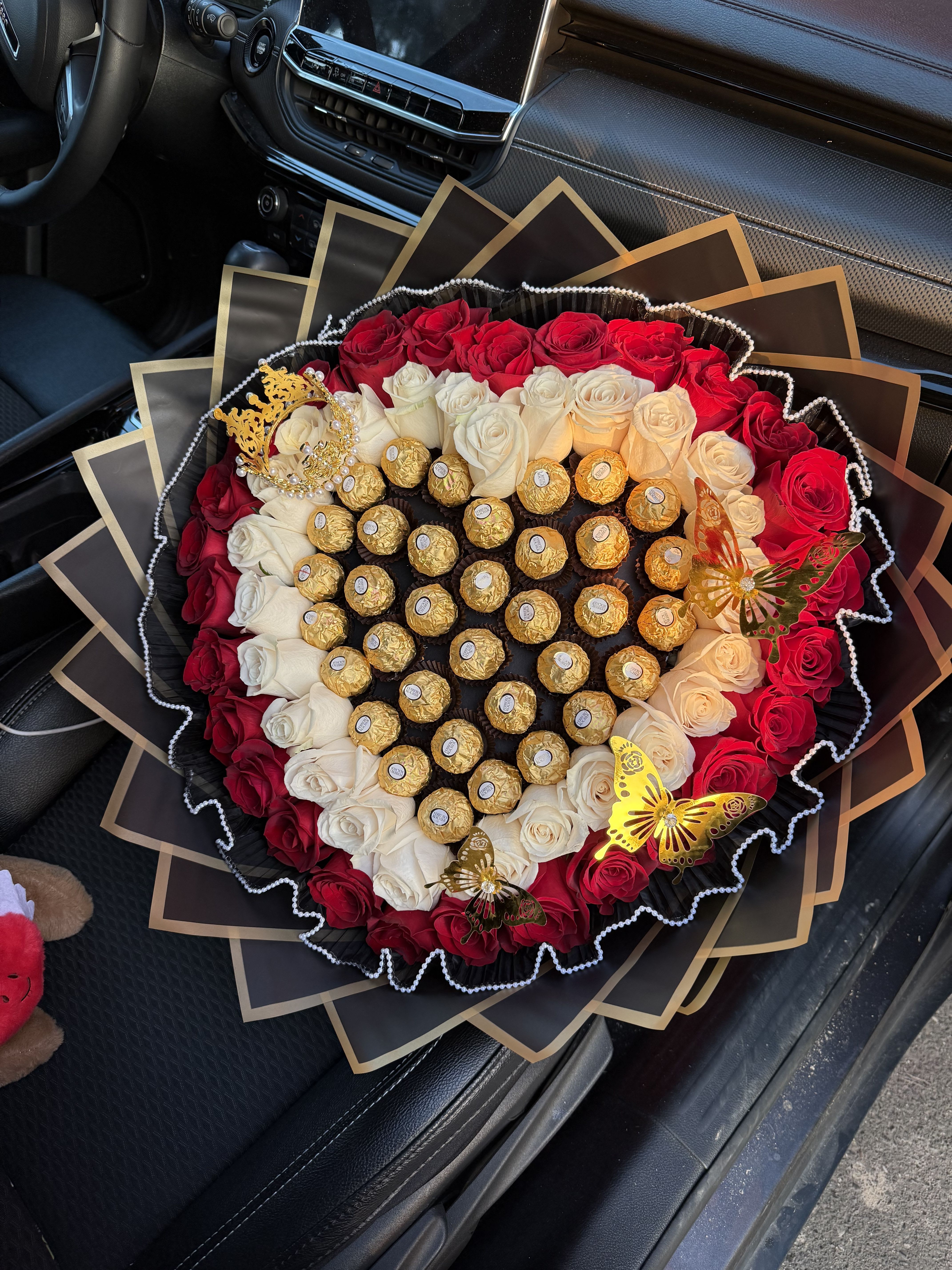 Heart-shaped bouquet of red and white roses with gold chocolates and butterfly accents