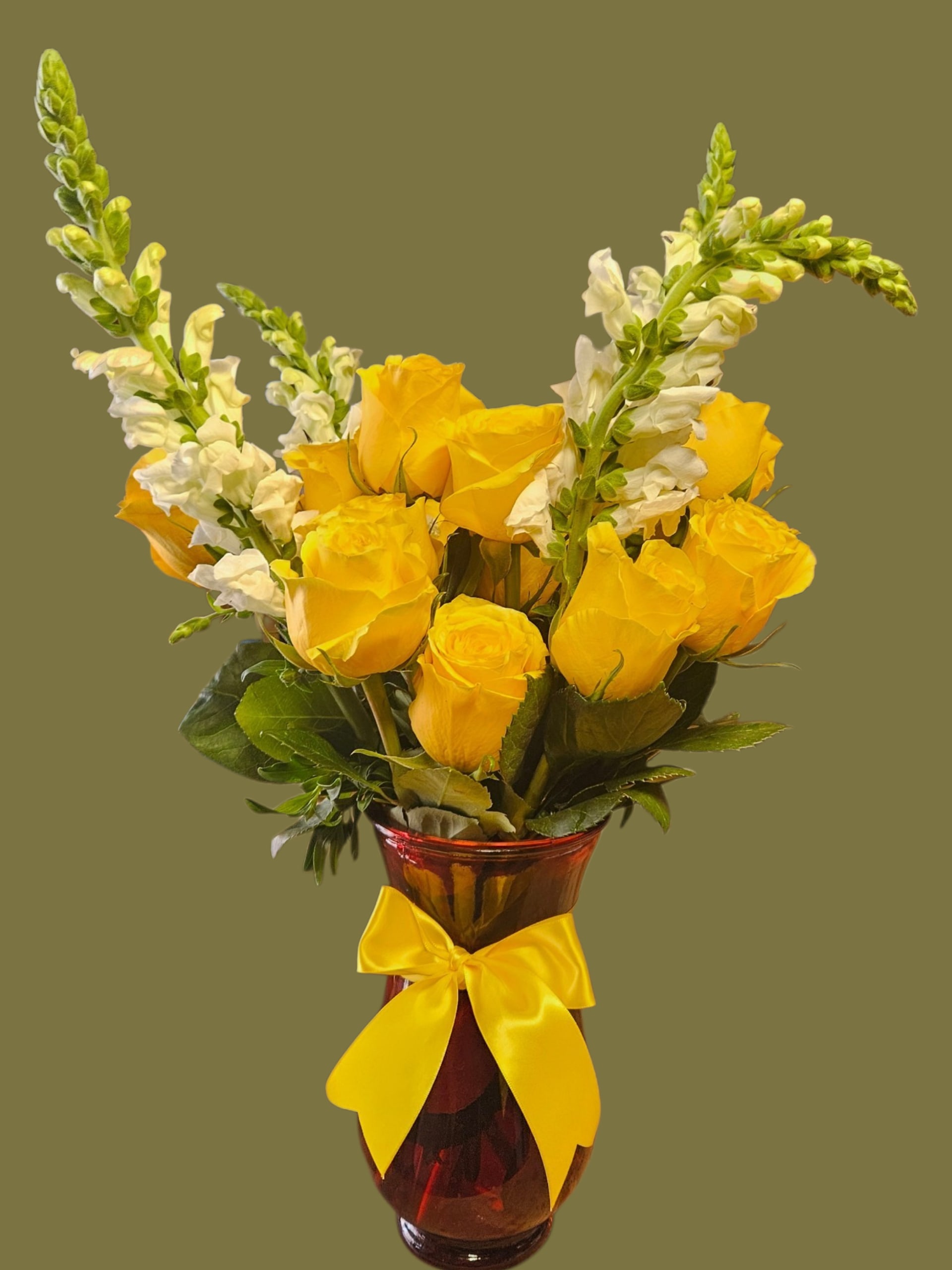 Garden  - Bright yellow roses gathered into a rounded cluster make an immediate sunny statement in this birthday bouquet, while tall white snapdragon spikes rise above the blooms to add graceful height and movement-perfect for birthdays, congratulations, or any cheerful gift. The warm red glass vase creates a striking contrast with the yellow blooms and green foliage, giving the person you're thinking of a bold, celebratory impression that reads both festive and polished.  Crafted in a translucent deep red glass vase and finished with a wide yellow satin ribbon, the arrangement pairs soft rose petals and crisp snapdragon texture for an uplifting visual and tactile mix. The upright, formal silhouette feels curated yet fresh, making it a versatile choice for spring occasions, office celebrations, or to brighten someone's day. Sized as a classic gift arrangement, it arrives ready to display-no fussing required-so the recipient will feel genuinely celebrated the moment it's unpacked.