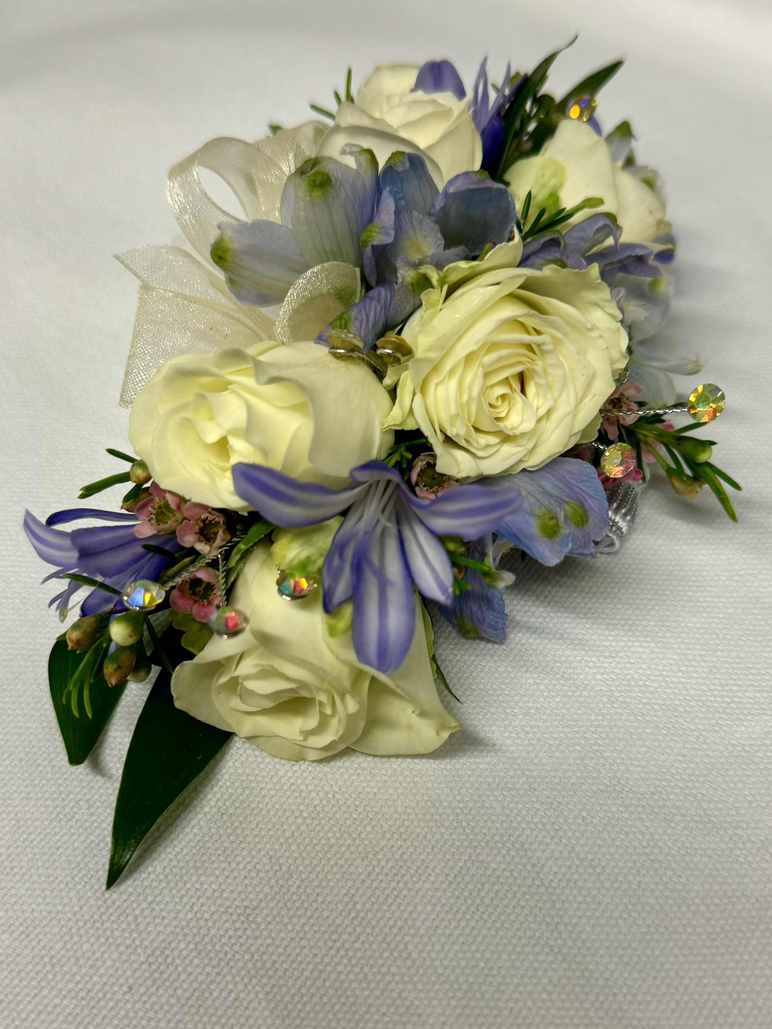 White and lavender floral corsage with ribbon and rhinestone accents