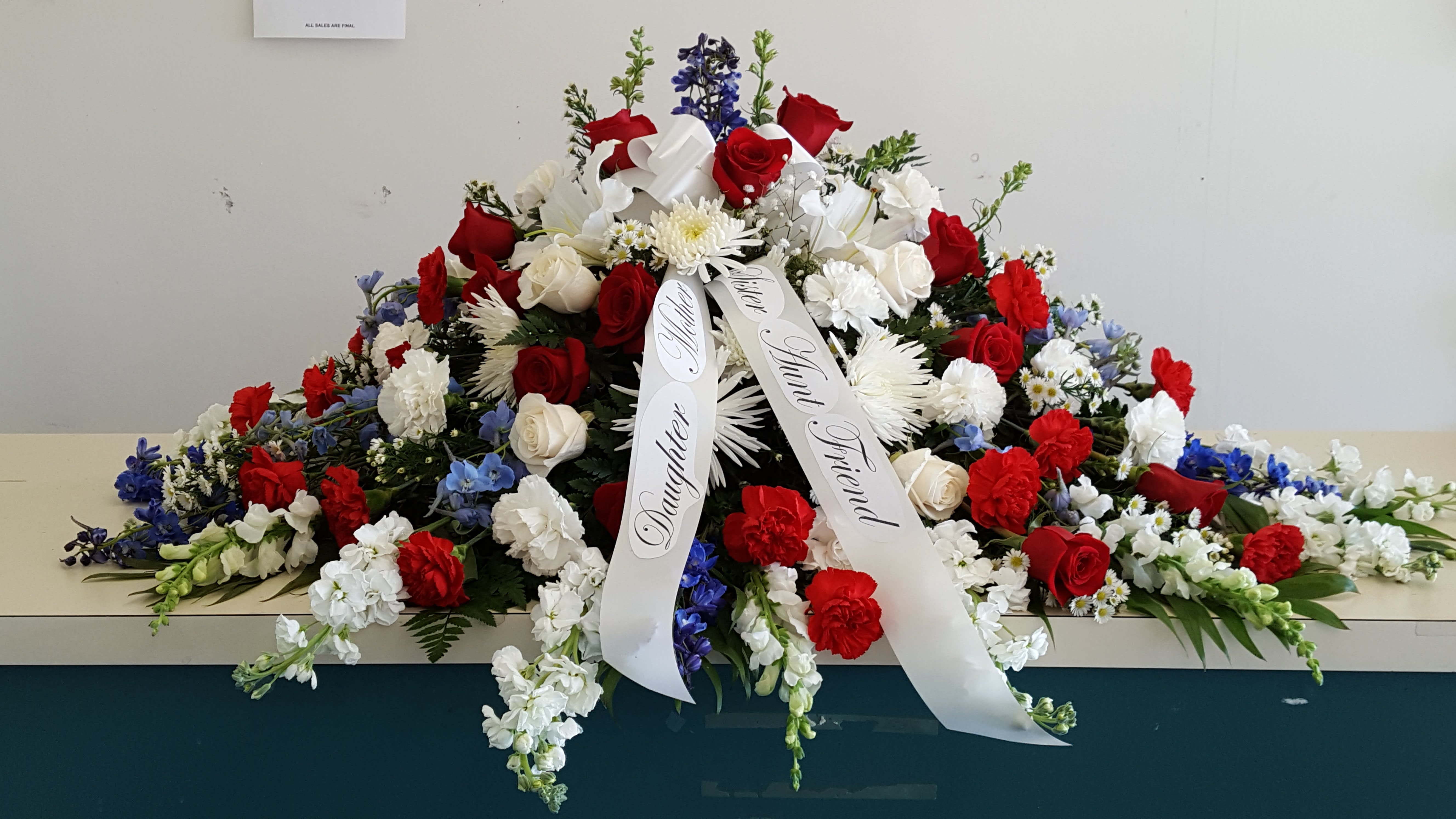 Large red, white, and blue funeral spray with ribbon streamers