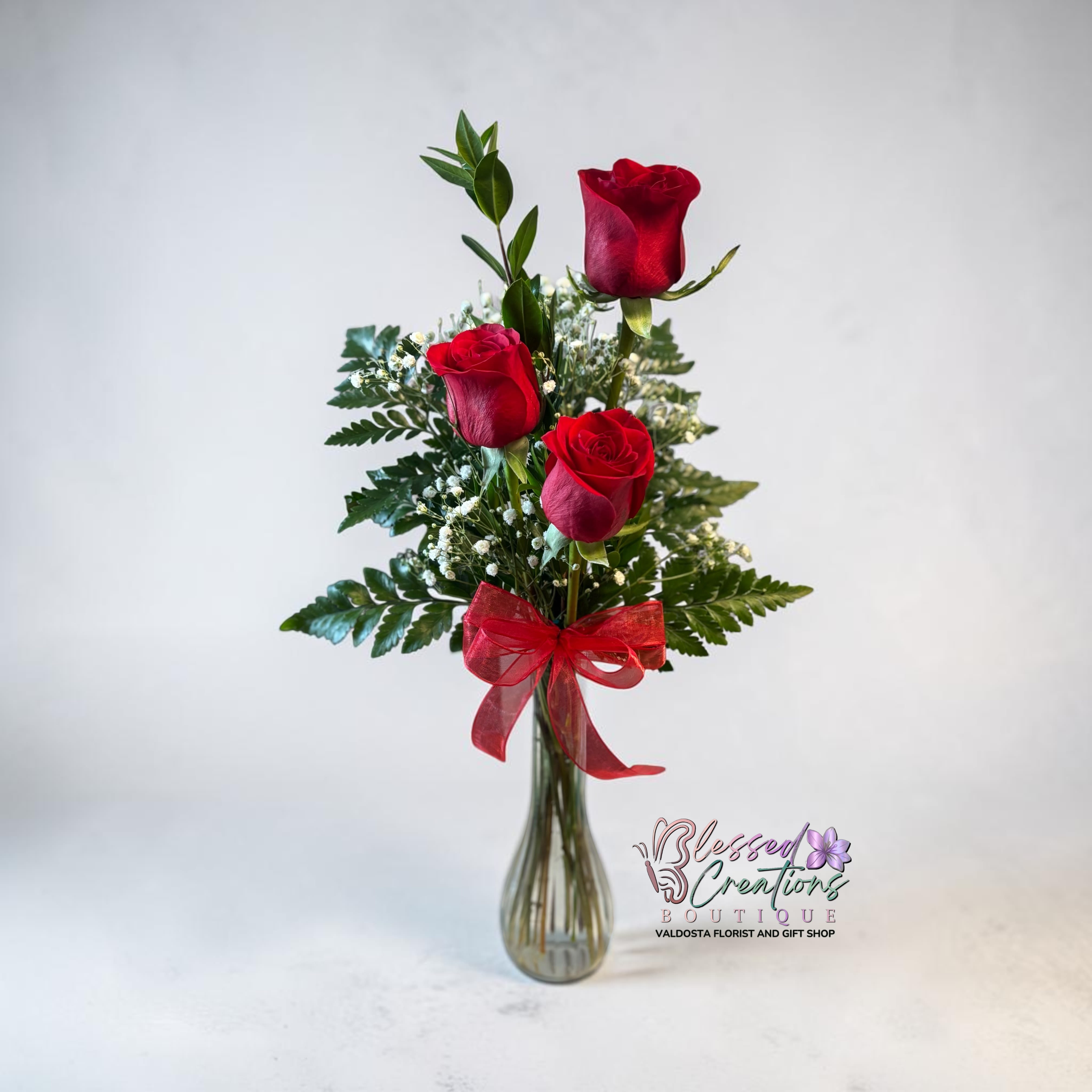 Trinity  - A timeless gesture of love, Trinity features three stunning red roses accented with delicate baby’s breath and fresh greenery, finished with a soft red bow