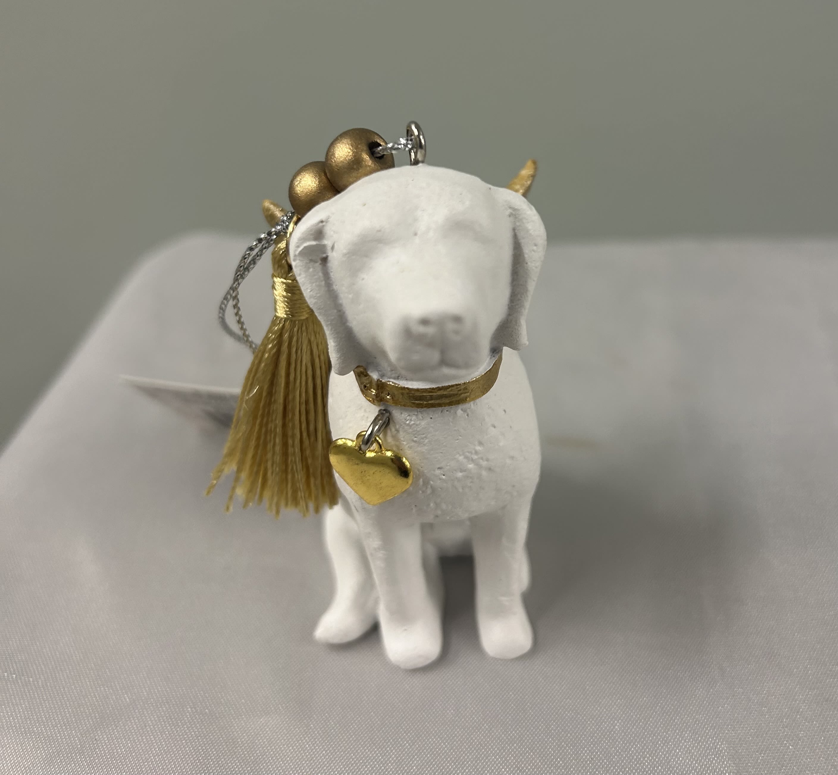 Small white dog figurine ornament with gold tassel and heart charm
