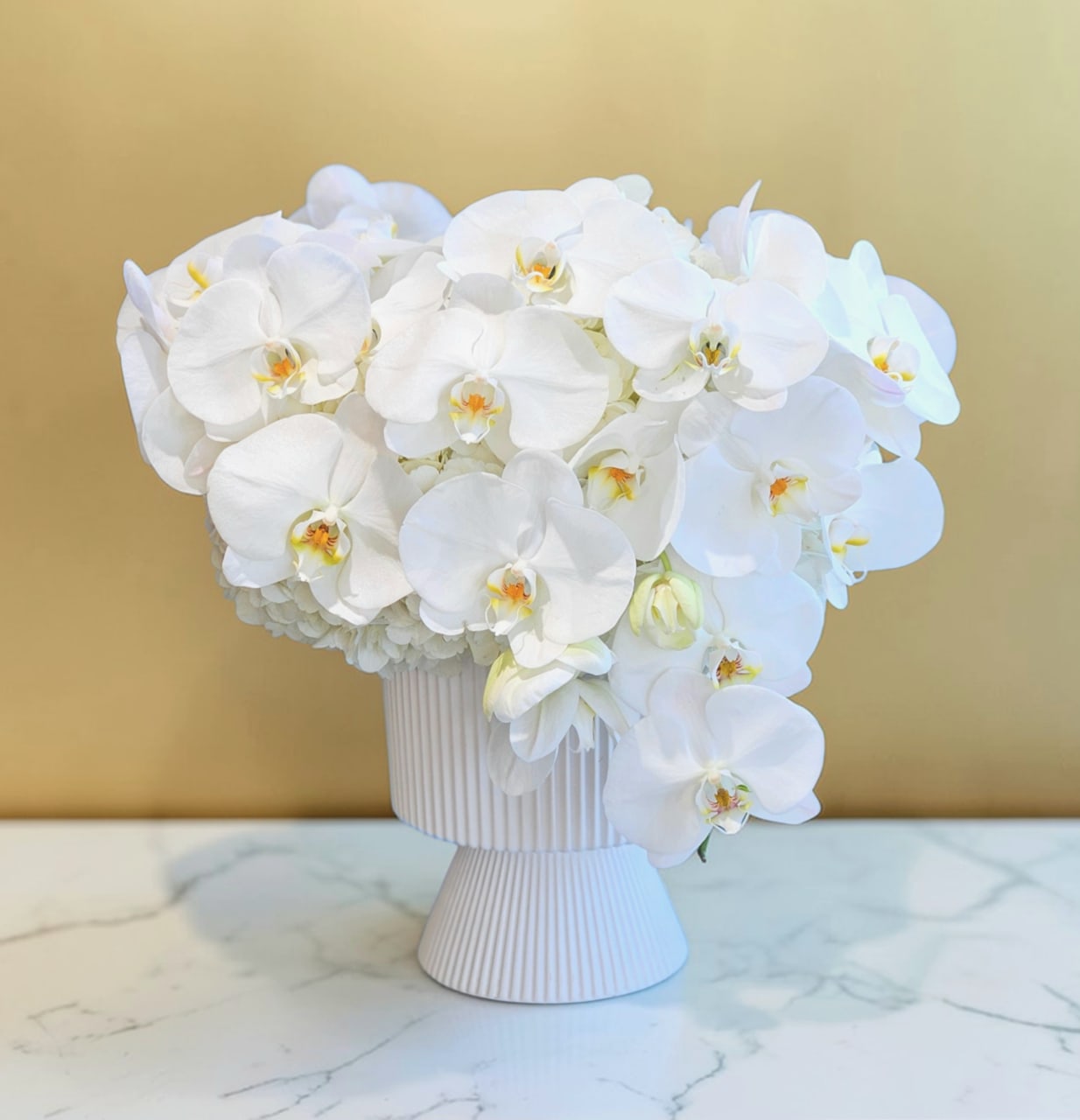 Lunar Orchids  - This is a luxurious, elegant, and predominantly white floral arrangement with Hydrangeas, and  White Phalaenopsis orchid , and slightly romantic feel in premium vase. 