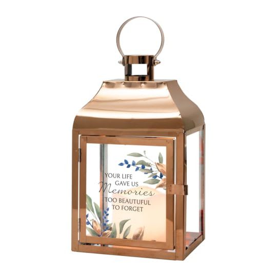 Copper metal lantern with glass panels and a memorial quote framed by small floral artwork.