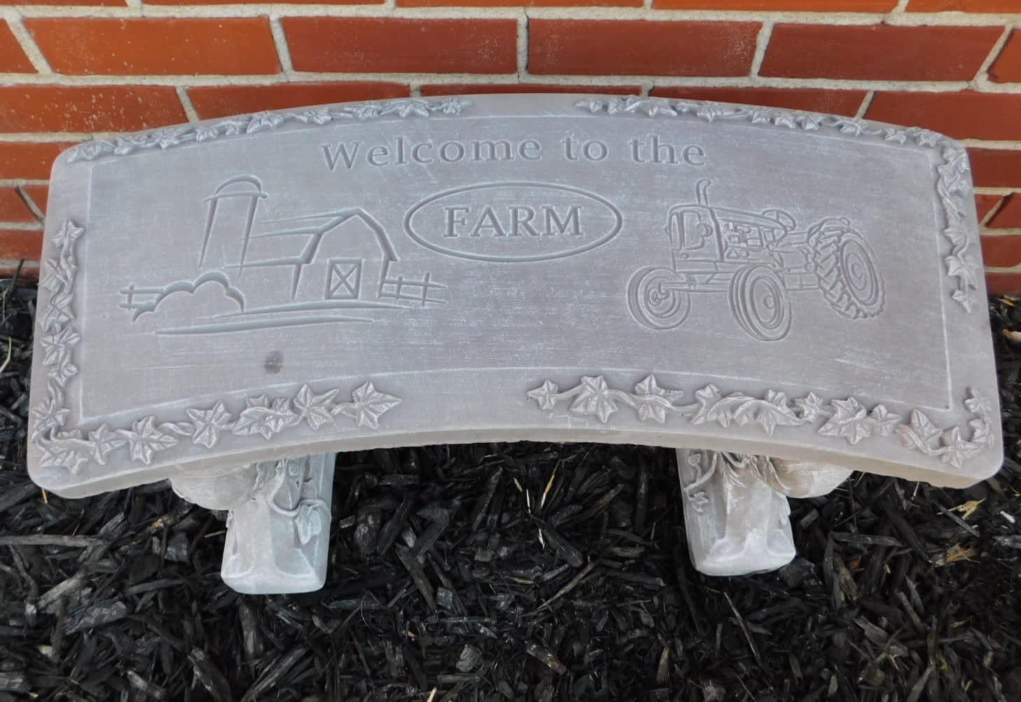 Stone sign reading welcome to the farm with a tractor and barn design