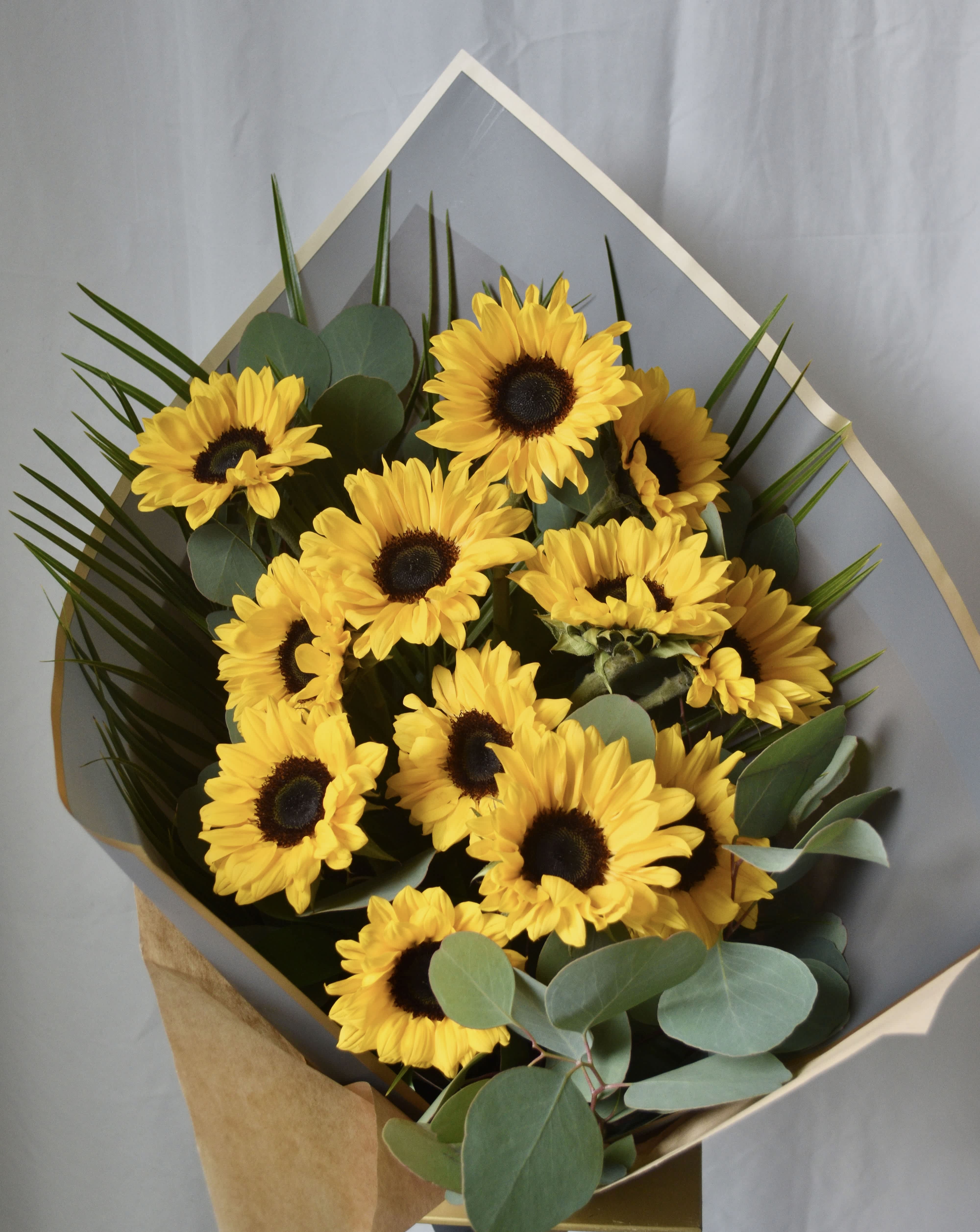 Bouquet of yellow sunflowers wrapped in gray paper