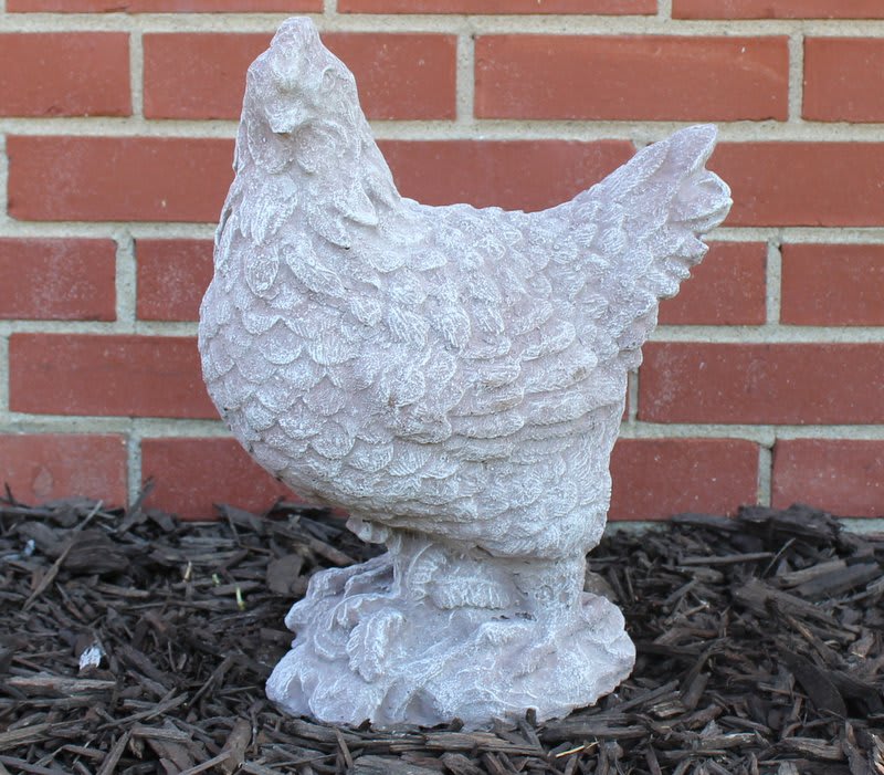 White chicken statue on mulch in front of a brick wall