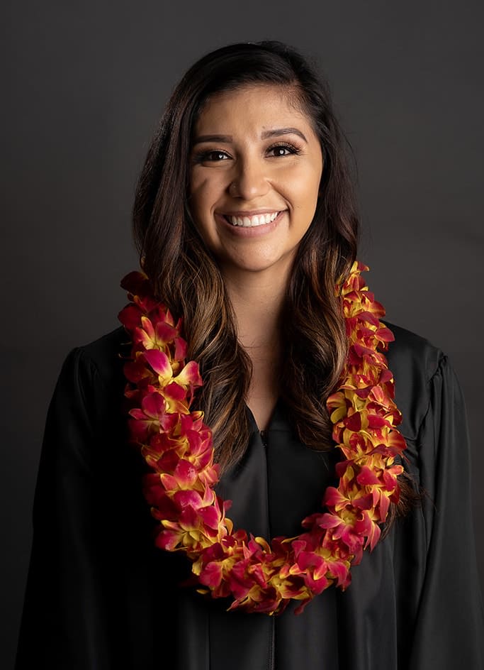 Woman wearing a red and yellow orchid lei over a black gown