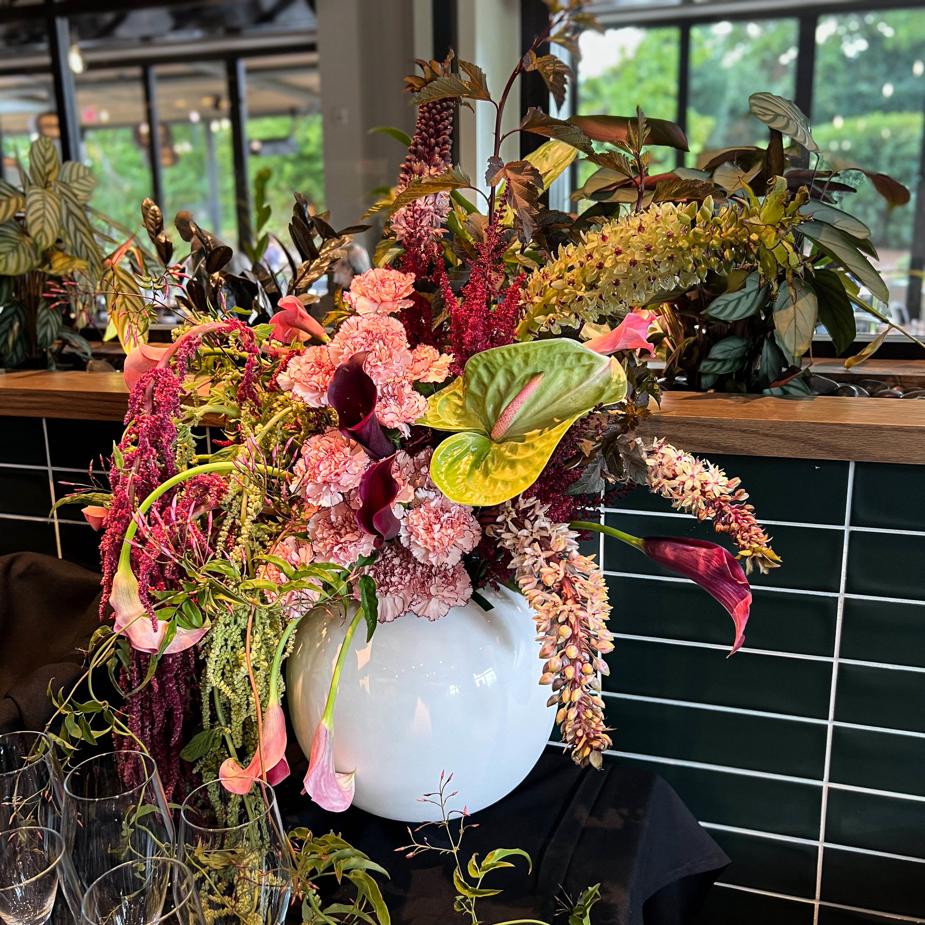 Large floral arrangement in a white vase with pink and burgundy blooms