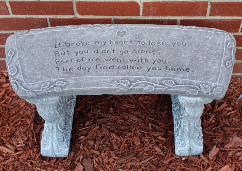 Gray memorial bench with an engraved sympathy message