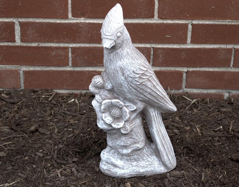 White bird statue holding a flower against a brick wall