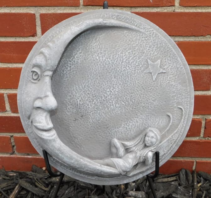 Round gray moon plaque with a face and reclining figure
