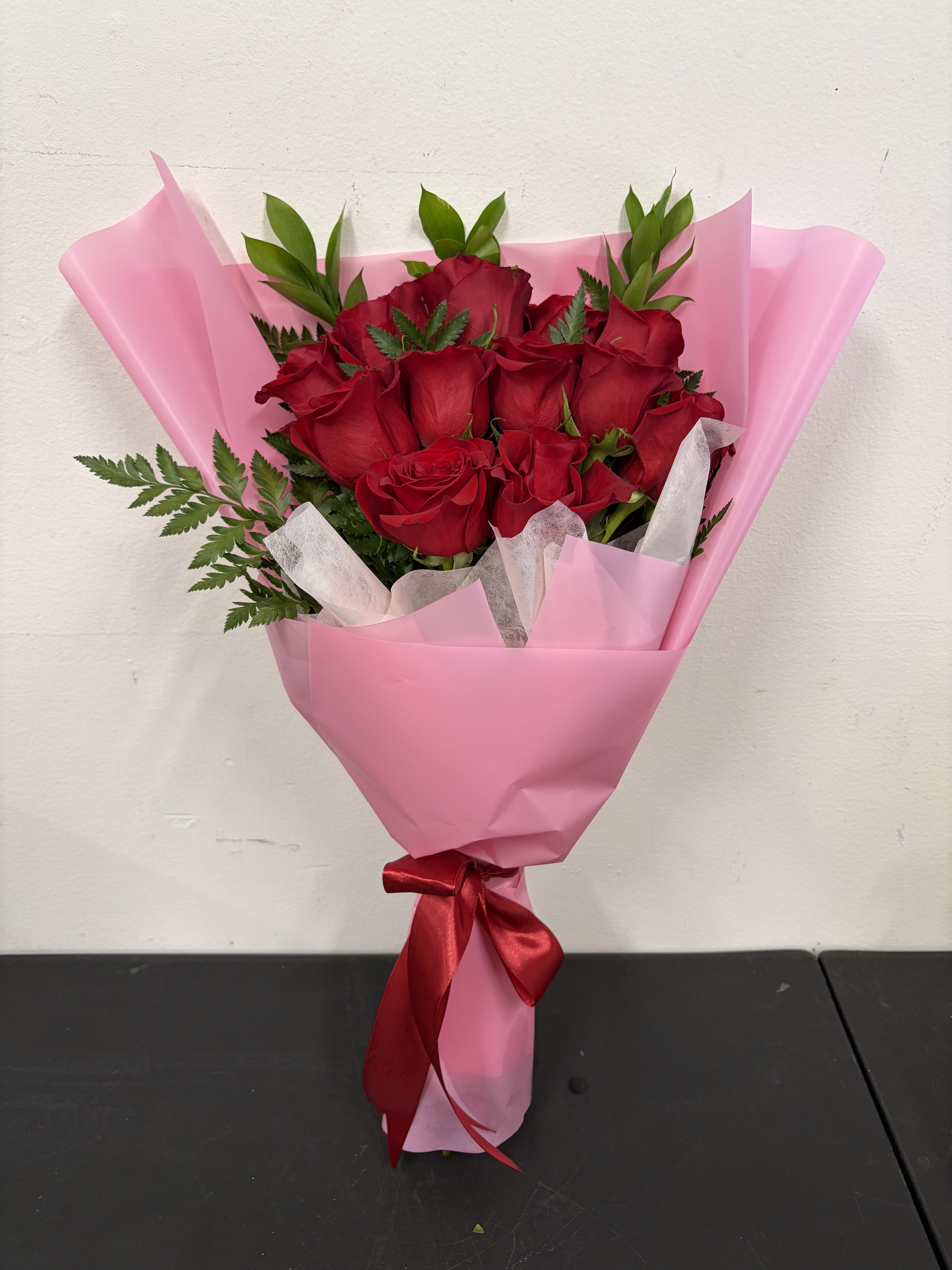 Love Bouquet - A classic bouquet of deep red roses wrapped in soft pink paper and finished with a red ribbon. Simple, elegant, and perfect for showing love and appreciation.