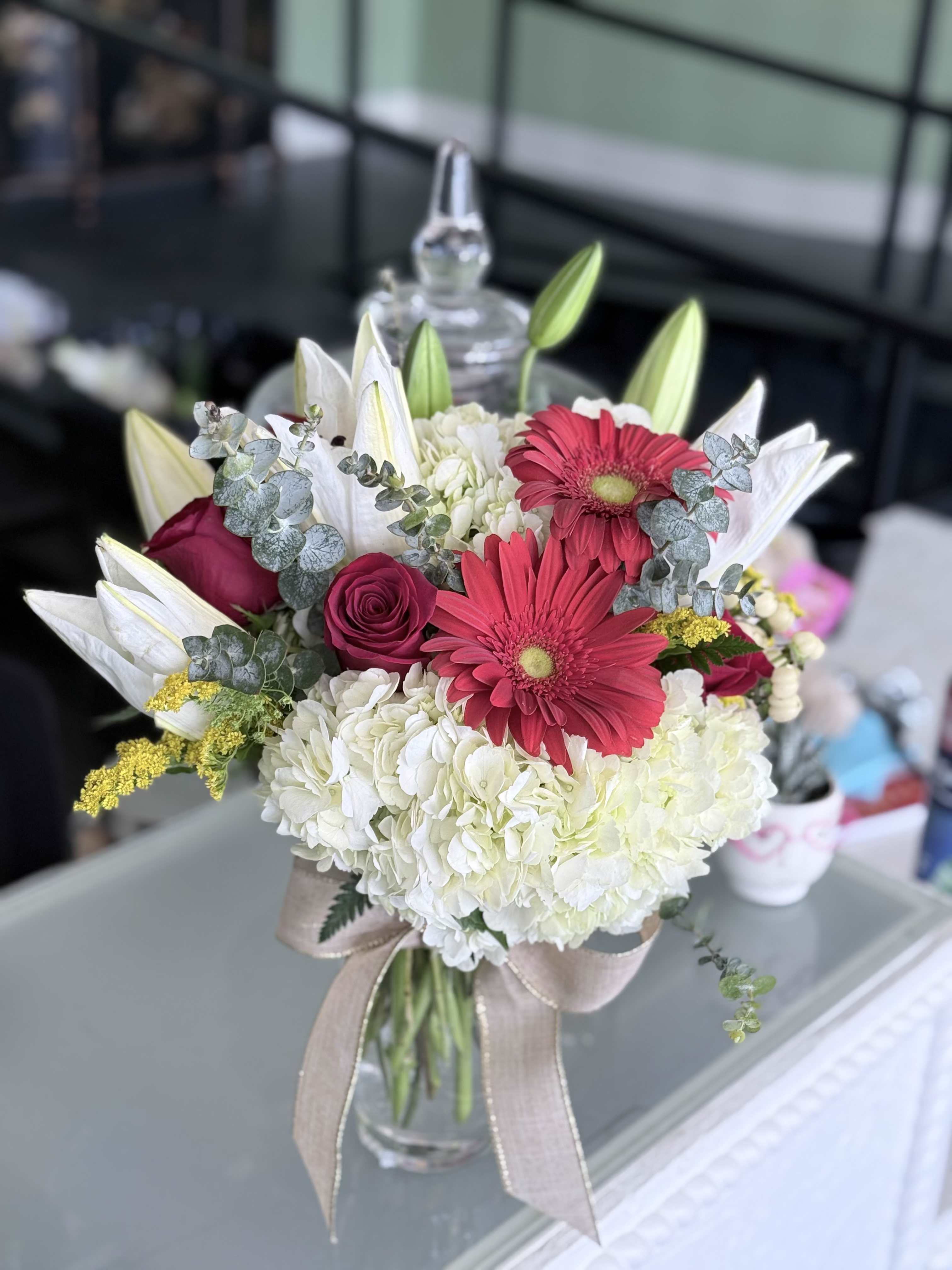 Blushing grace - White Hydrangeas, red roses, red Gerber daisies, white Lillys. 