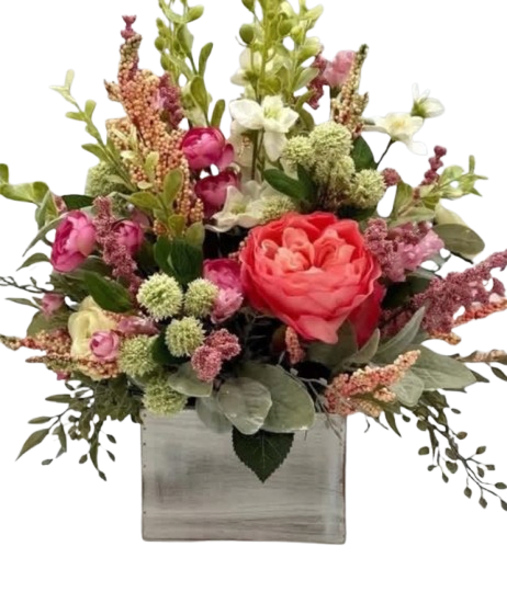  Coral Meadow Charm - Coral Meadow Charm is a fresh and enchanting floral arrangement inspired by the beauty of a blooming countryside garden. Featuring a stunning coral rose as its focal point, accented with delicate pink blooms, textured seasonal florals, soft green button accents, and lush greenery, this charming design is arranged in a rustic wooden cube container. Its warm coral and blush tones paired with natural textures create a stylish and inviting look, making it a perfect gift for birthdays, thank yous, celebrations, or simply brightening someone’s day.
