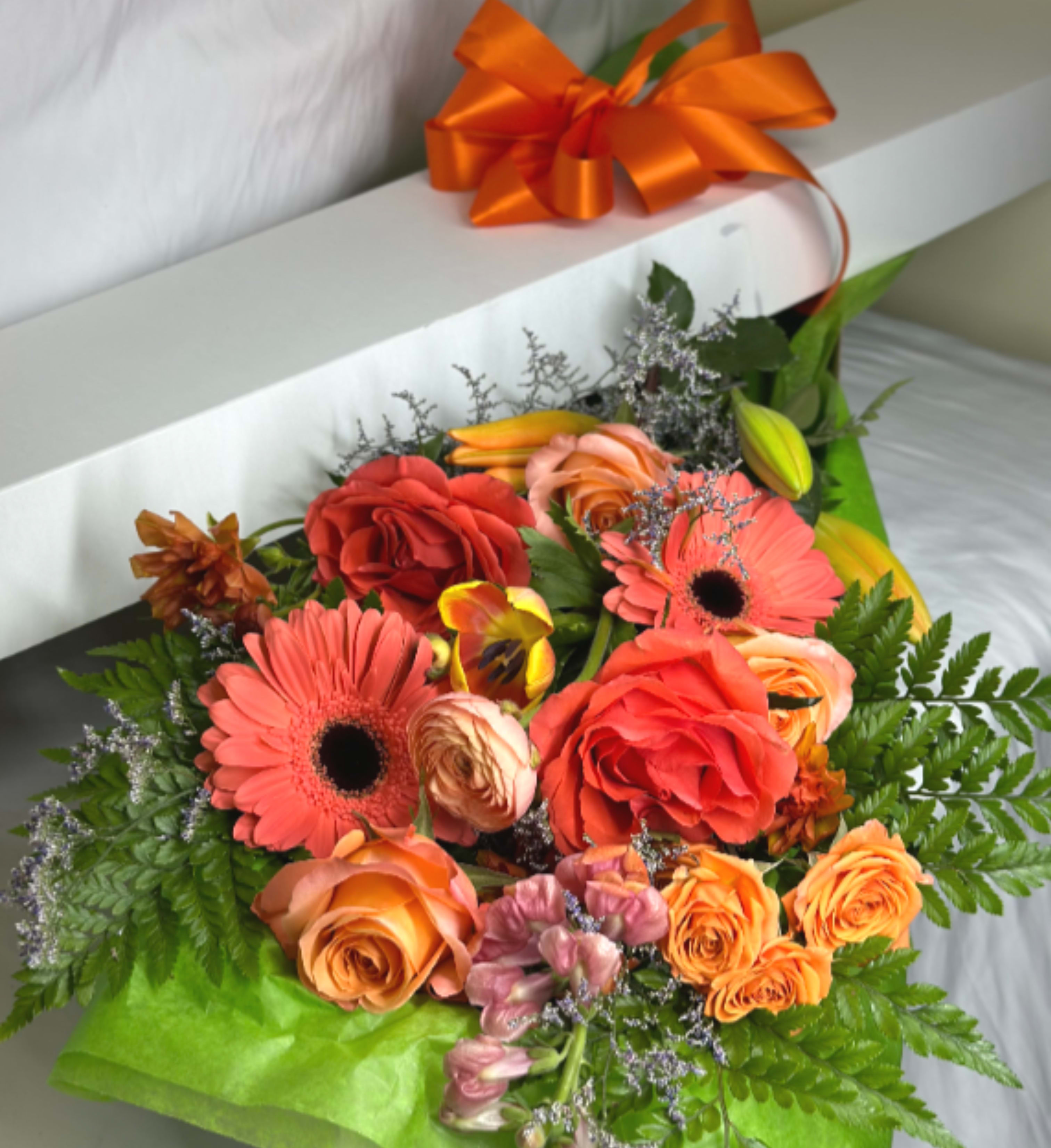 The Peach and Orange Box - If you want to bring joy to someone, just send a boxed bouquet of the loveliest flowers around! We will curate the freshest seasonal blooms in stunning shades of Peach, coral, and orange! Each hand designed grouping will be unique. The pictured flowers are an example of the lovely blossoms we incorporate into a lavish boxed presentation with a coordinating ribbon. PLEASE NOTE, no vase is included