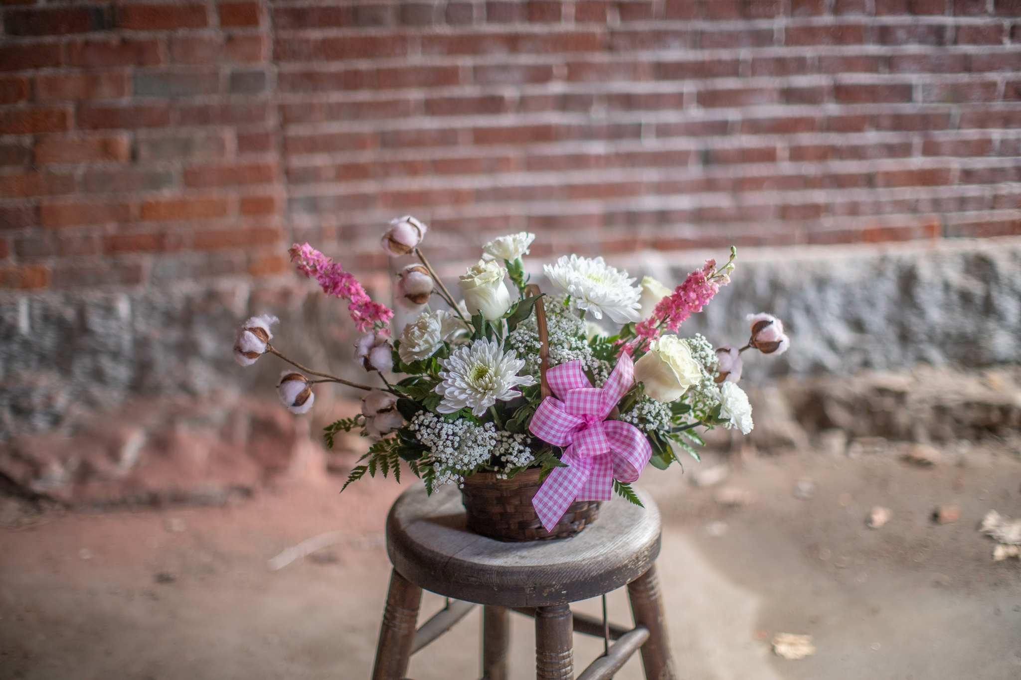 Basket arrangement of white and pink flowers with a gingham ribbon