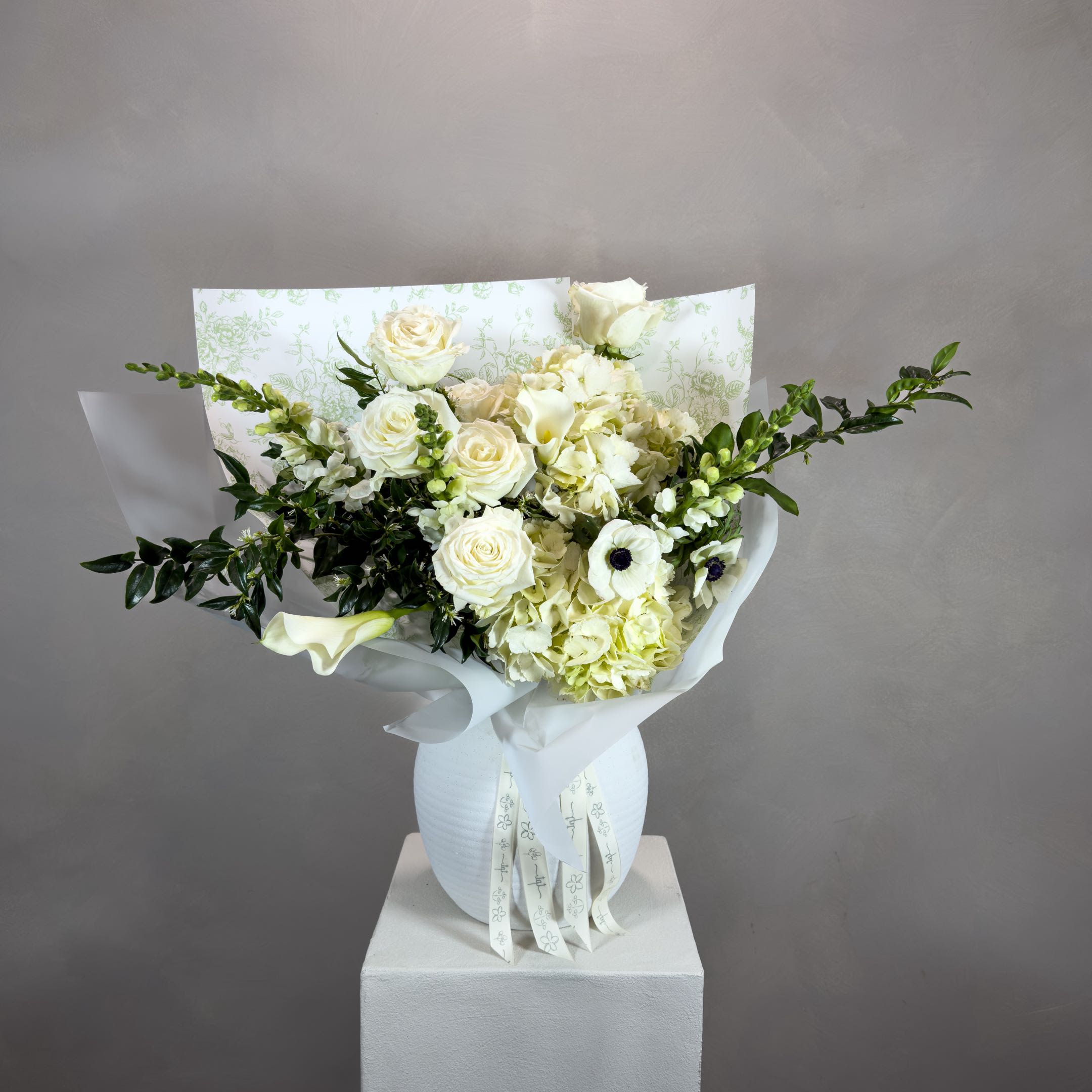 For Eomeoni in White - A soft, all-white bouquet composed in layered tones - bringing together seasonal and classic flowers in a warm, gentle palette. Designed intuitively, each arrangement is one of a kind, allowing texture, movement, and color to shape the final form.  What’s Included:  – Seasonal flowers in white tones – Handwritten note + care instructions – Carry-out bag – Water source to keep stems fresh – Bouquets with 18+ stems include a water pouch for transport  Please Note:  Images are for inspiration only. We do not replicate past designs or recreate another florist’s work. Each bouquet is uniquely handcrafted with care and intention.