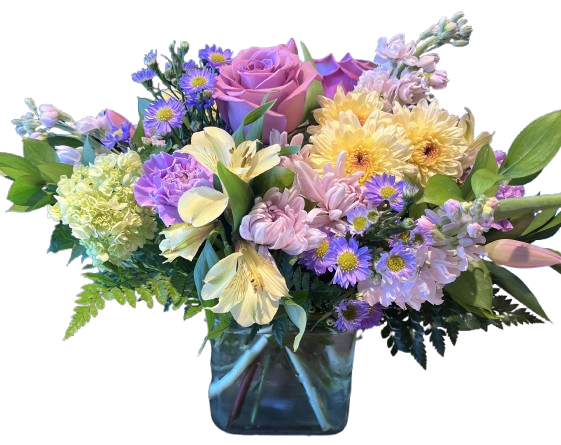 Blushing Meadow Garden - Blushing Meadow Garden is a soft and graceful floral arrangement filled with the beauty of a blooming spring meadow. Featuring elegant lavender roses, delicate pink blooms, cheerful pastel daisies, fresh hydrangea, and accents of seasonal wildflowers, this design is arranged in a modern glass cube vase for a lush garden-inspired look. Its gentle blend of blush, lavender, and creamy tones makes it a perfect gift for birthdays, celebrations, thank yous, or simply brightening someone’s day.