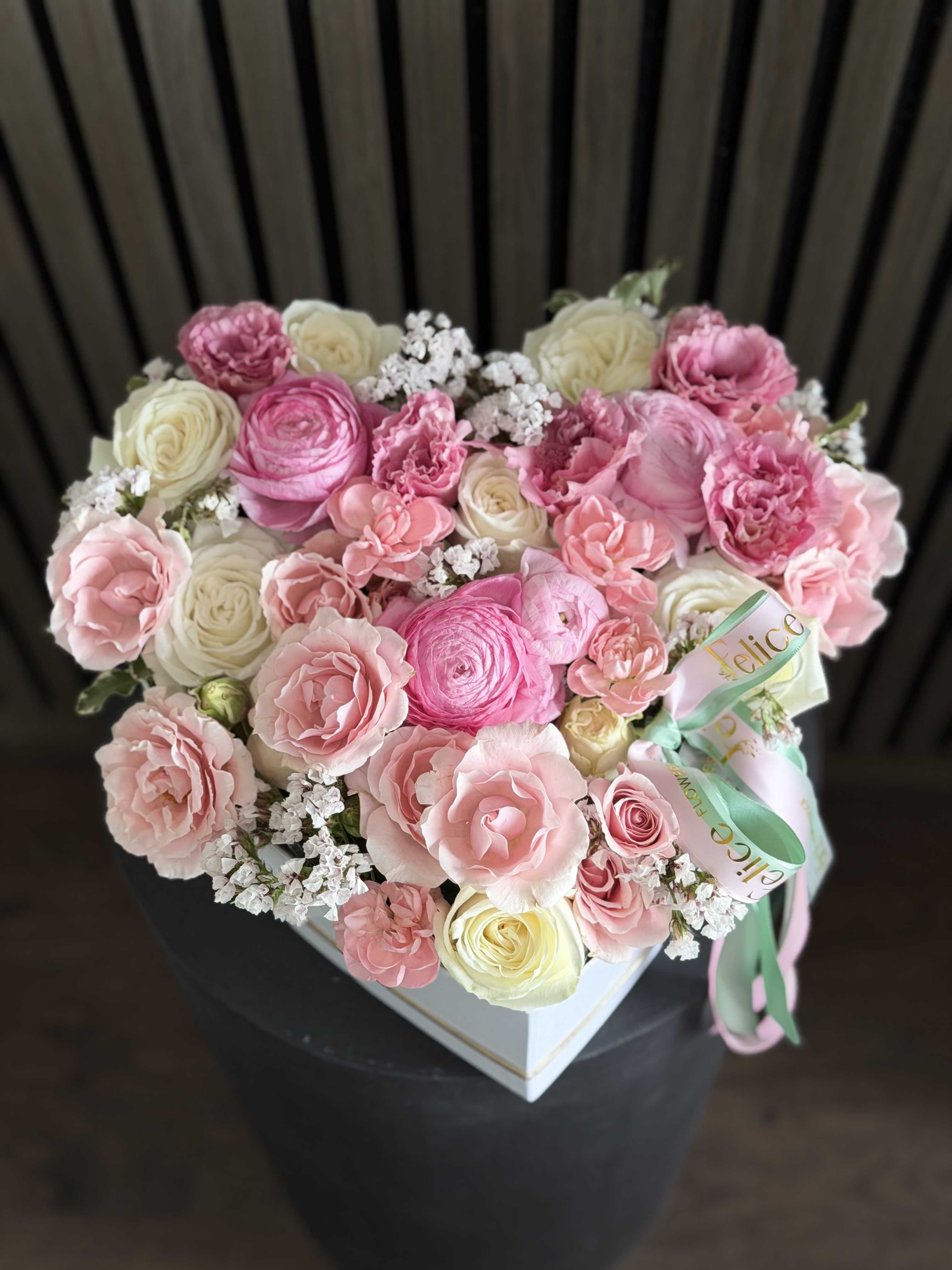 Blush Heart Luxury Box - A luxurious heart-shaped flower arrangement designed in soft blush pink and creamy white tones, featuring premium roses, ranunculus, spray roses, and delicate filler flowers. This elegant floral box is crafted to express love, tenderness, and refined beauty. The heart shape makes it a perfect romantic statement, while the soft color palette adds a touch of sophistication and charm. Designed in a premium box with signature ribbon detailing, this arrangement is ideal for making unforgettable moments. Perfect for Valentine’s Day, Anniversary, Love and Romance, Birthday, and Special Occasions. Please note: due to seasonal availability, some flowers may be substituted. However, the shape, color palette, size, and overall luxurious look will remain consistent with the photo. Handcrafted by Felice Flowers &amp; Design.