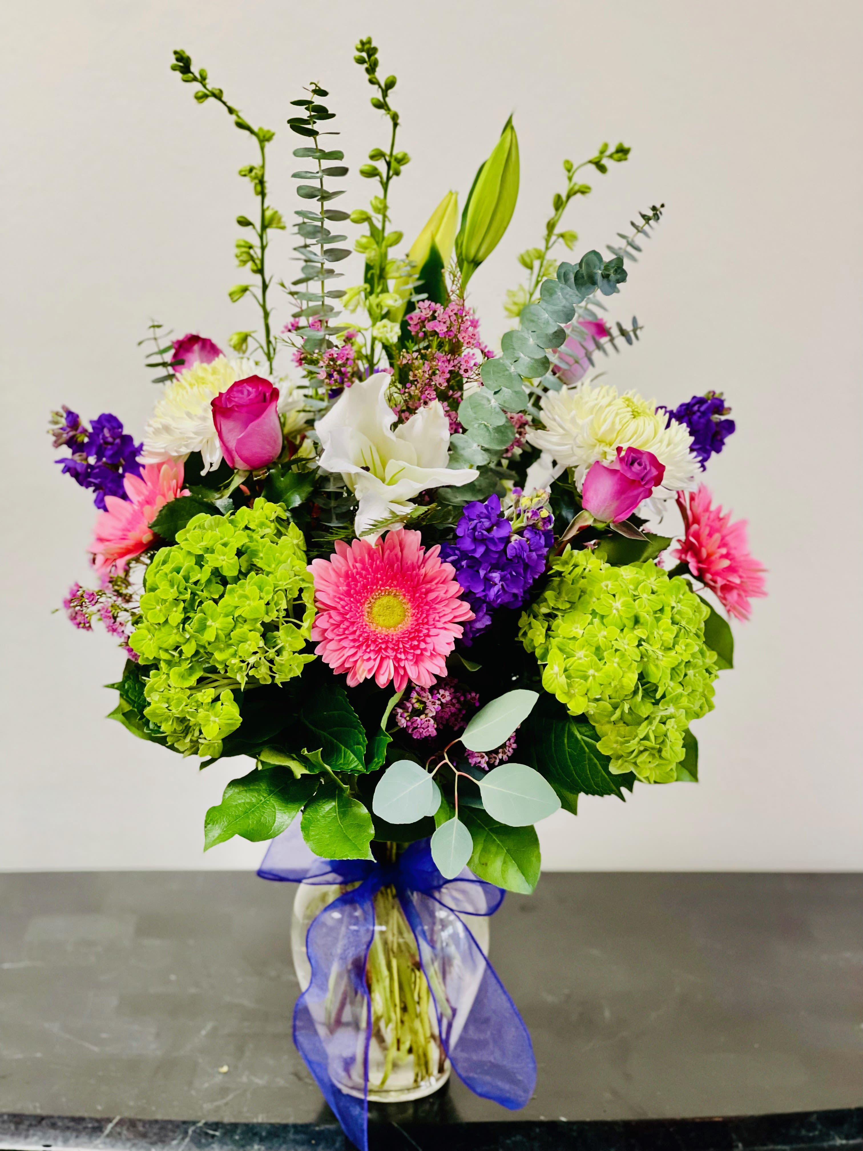 Mixed bouquet with pink roses, lilies, gerbera daisies, and hydrangeas in a glass vase