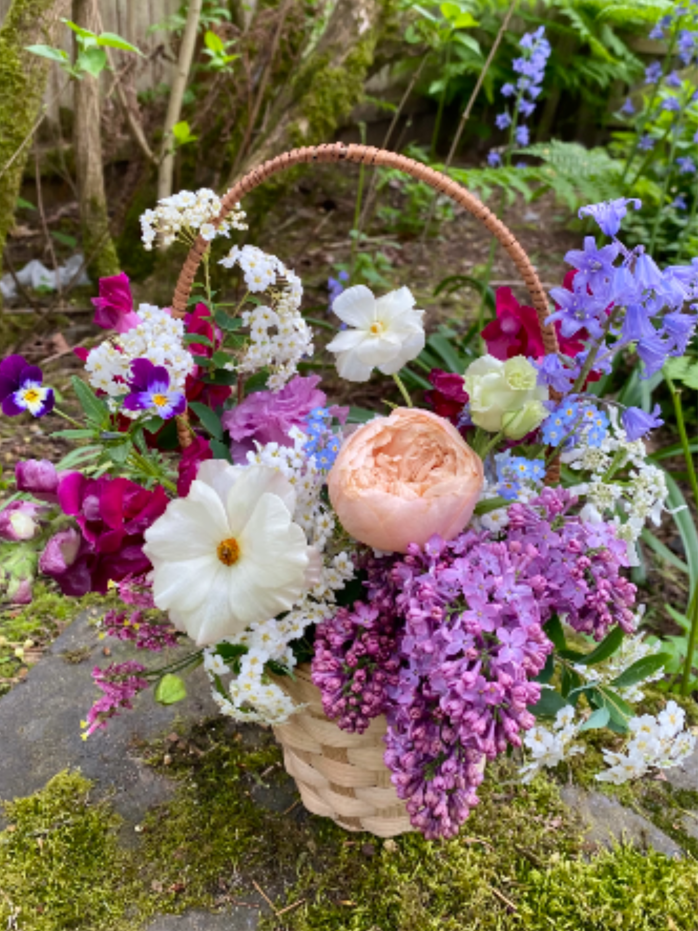 Basket of mixed pastel flowers with a woven handle