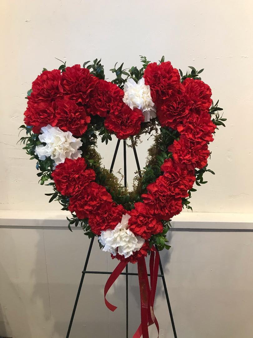Heart-shaped wreath of red and white carnations on an easel