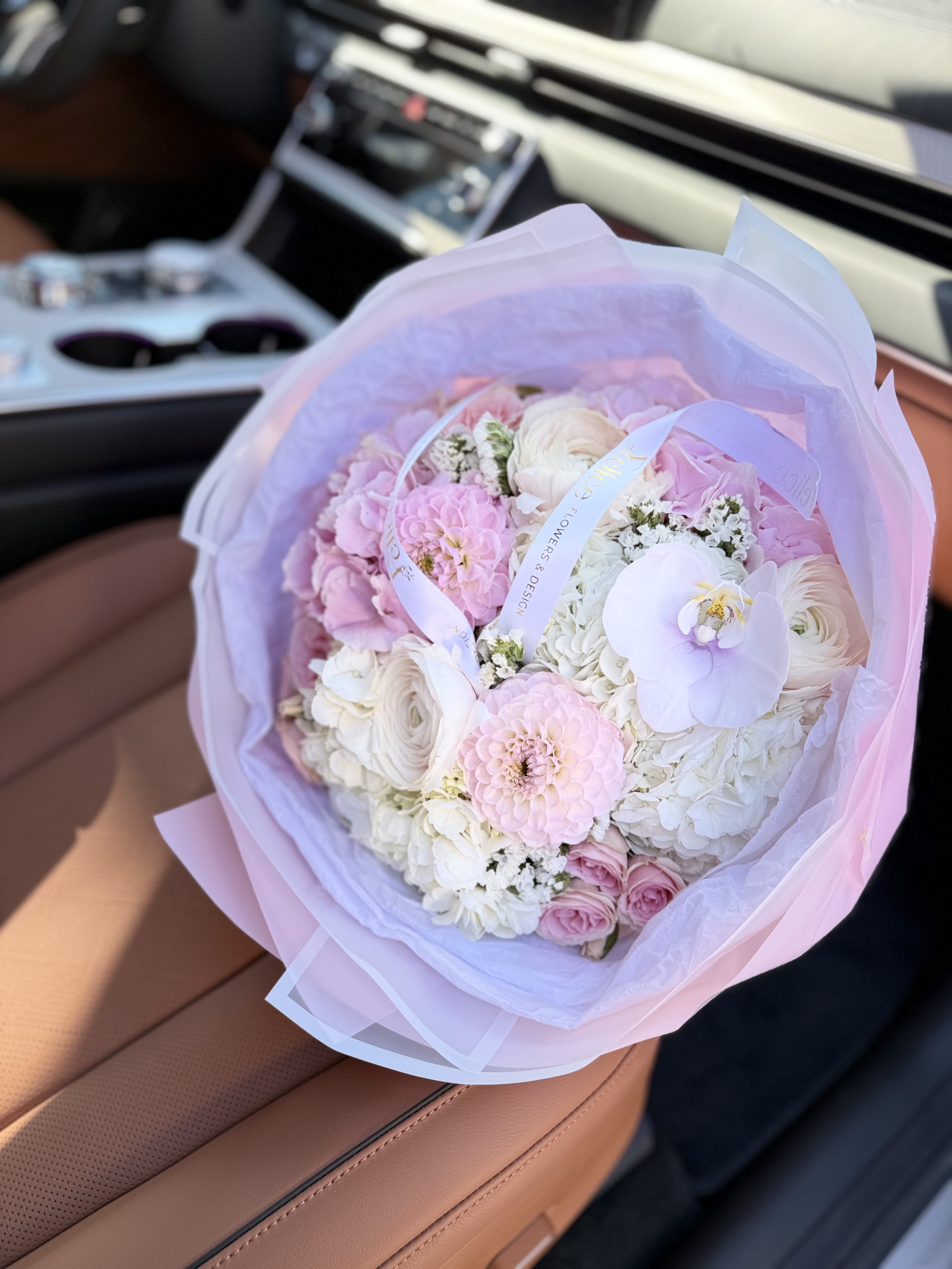 Signature Blush Luxury Bouquet - A refined luxury bouquet designed in a compact, full style featuring soft blush and ivory tones with premium blooms. This elegant arrangement includes roses, ranunculus, hydrangea, and a delicate orchid accent, creating a sophisticated and modern floral design. The tightly arranged structure enhances the richness and fullness, giving it a truly luxurious appearance. Wrapped in premium paper and finished with signature Felice Flowers &amp; Design ribbon, this bouquet is crafted for clients who appreciate high-end floral design. Perfect for Anniversary, Birthday, Romantic occasions, or luxury gifting. Please note: flower varieties may vary due to seasonality while maintaining the same color palette and premium look.