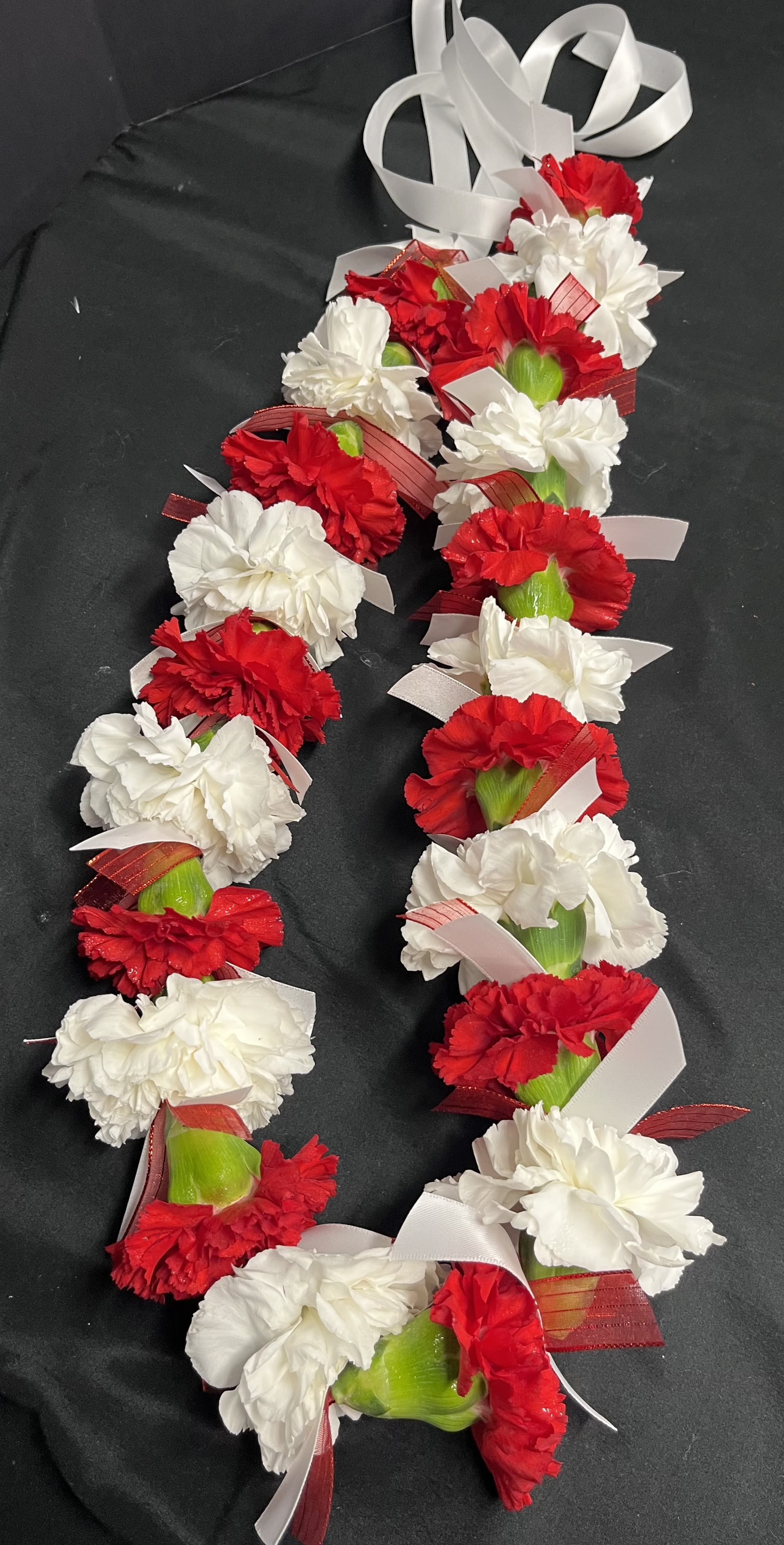 Carnation Lei - Our carnation lei is hand designed by our florists.  If you want a color other than pictured, put the color choice in the pick up notes. Or you can call our number @435-652-8998. to order on the phone. we need 3 days notice for other colors.