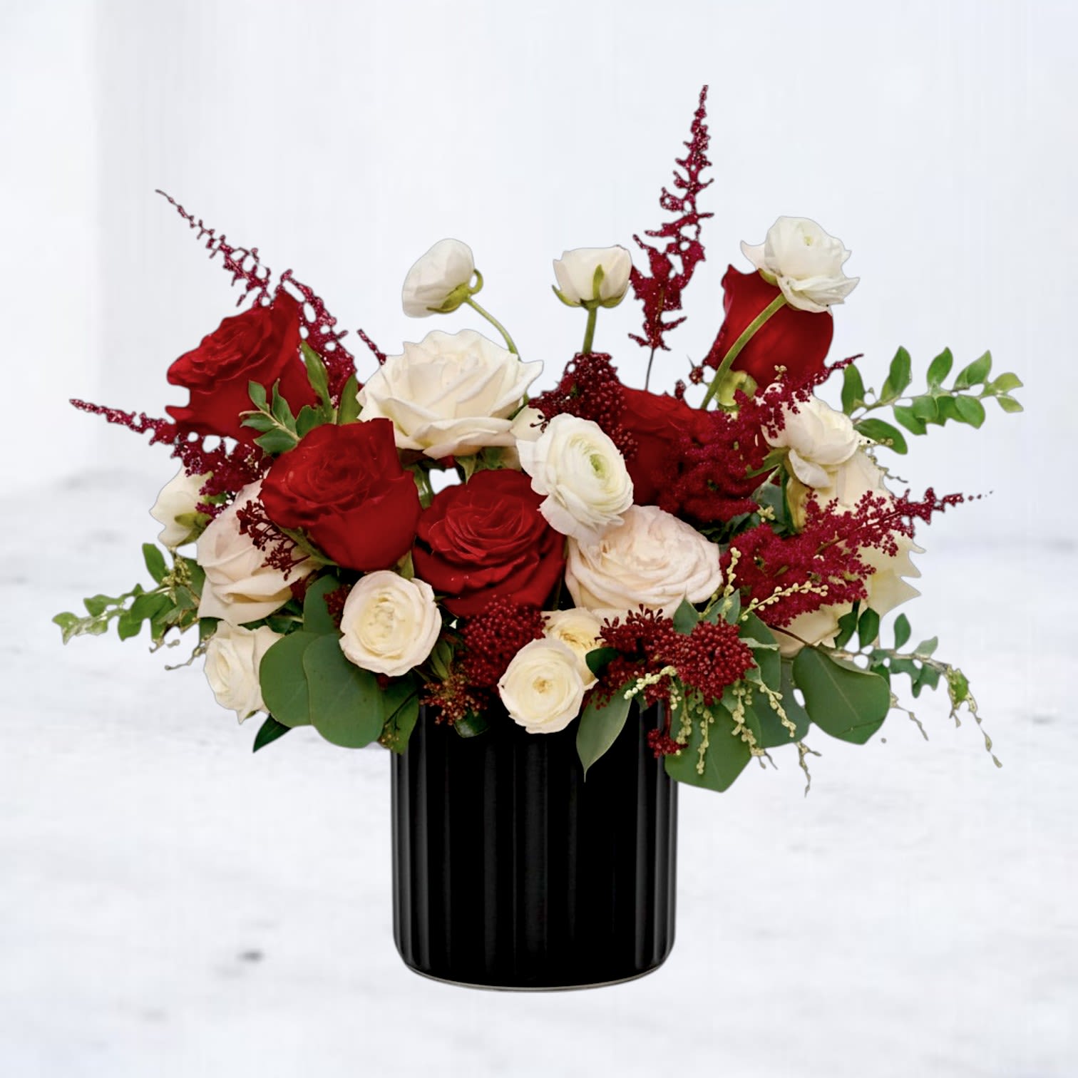 Red and white rose arrangement in a black vase