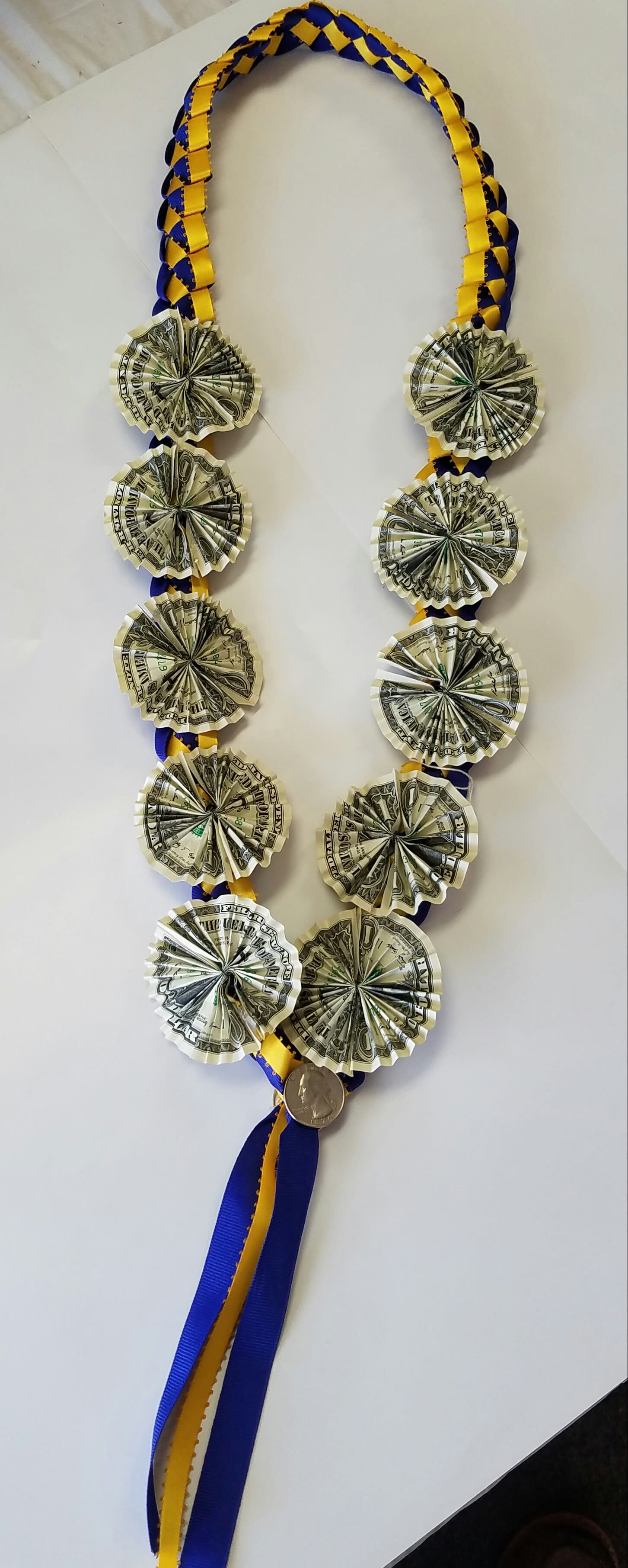 Ribbon lei with folded dollar bills and a coin pendant