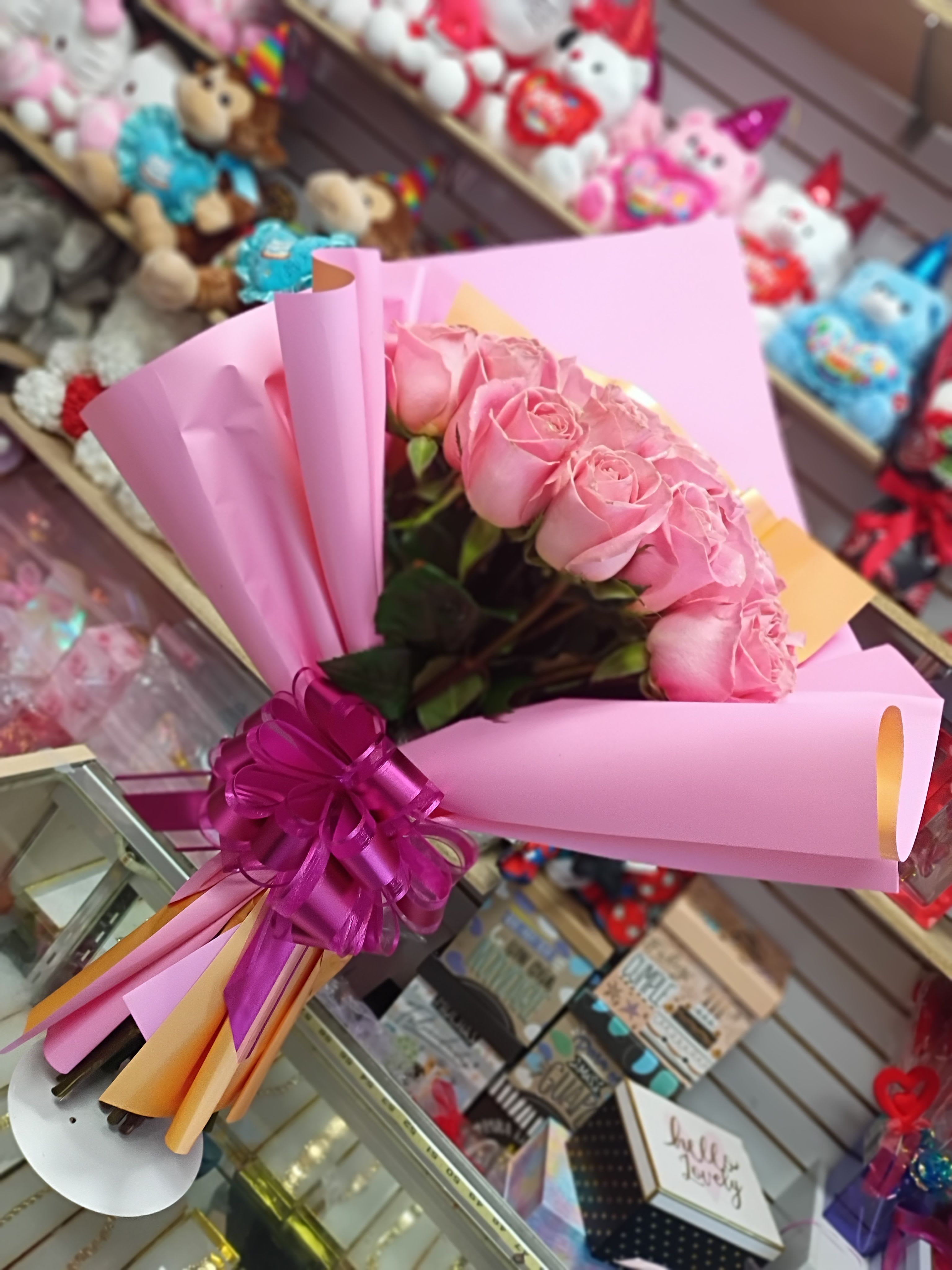 Pink rose bouquet wrapped in pink paper with a purple ribbon