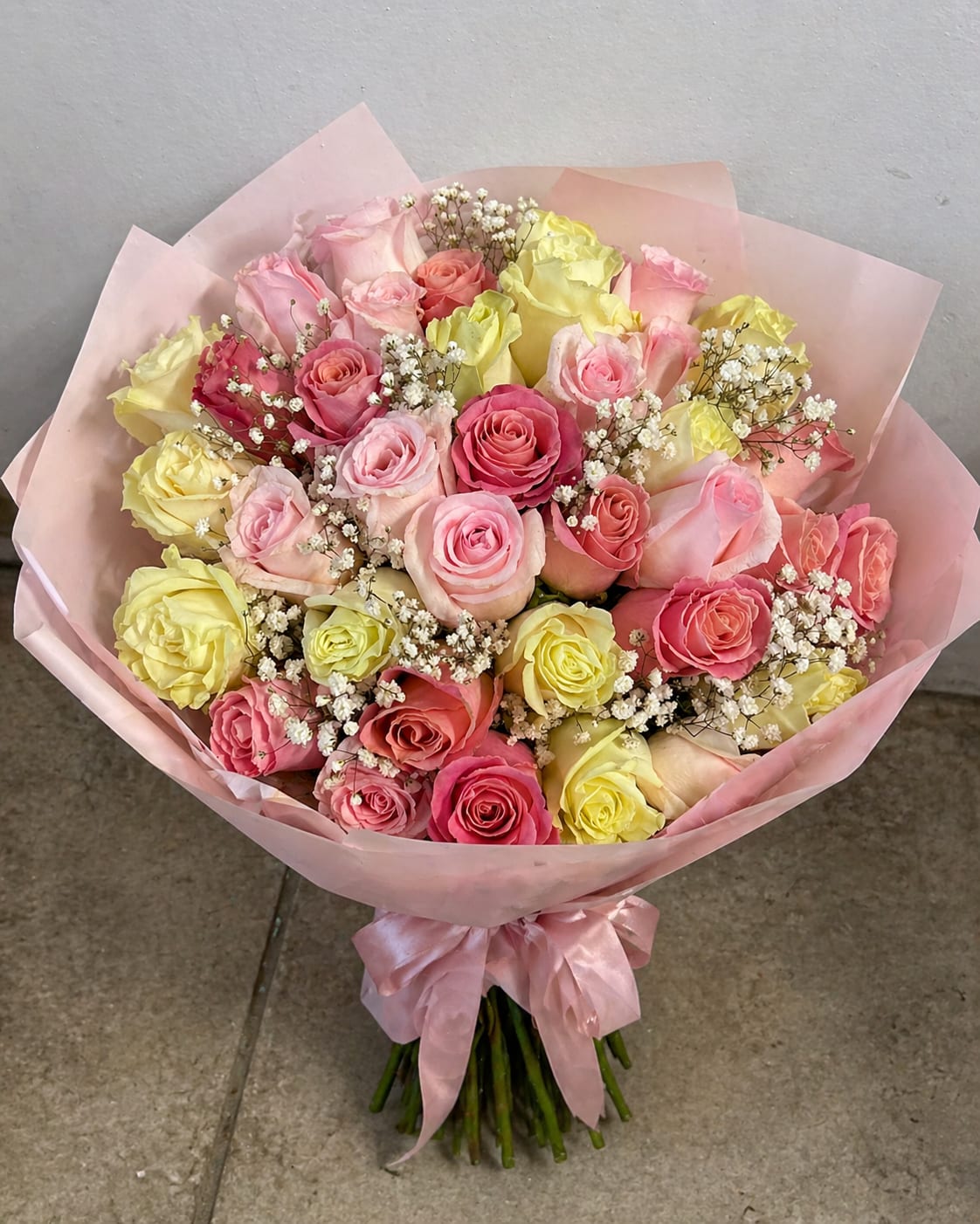 Blush &amp; Buttercream - This bouquet features a blend of blush pink, warm peach, and buttery yellow roses, delicately accented with airy baby’s breath. Wrapped in translucent blush paper and finished with a satin ribbon, it gives that perfect “light and lovely” feel. 