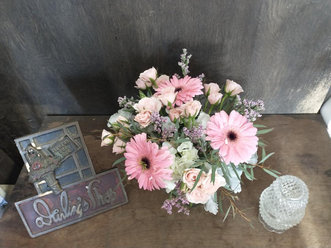 Pink gerbera daisies and pale roses arranged on a table