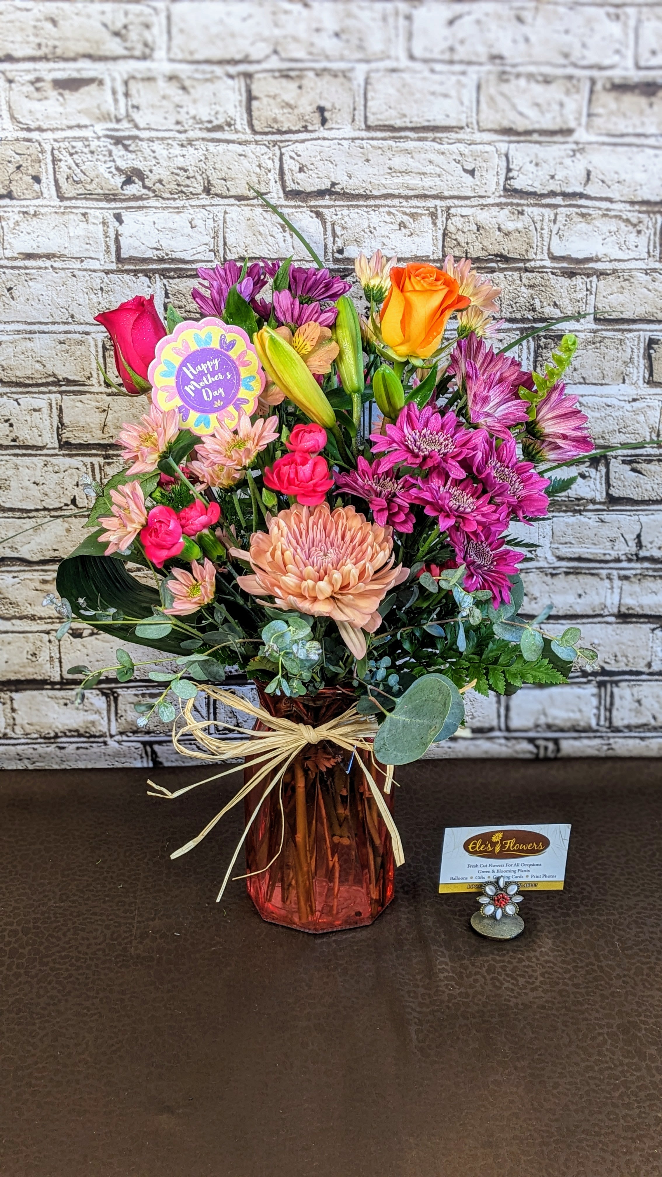 Mixed bouquet in a pink glass vase with roses and chrysanthemums